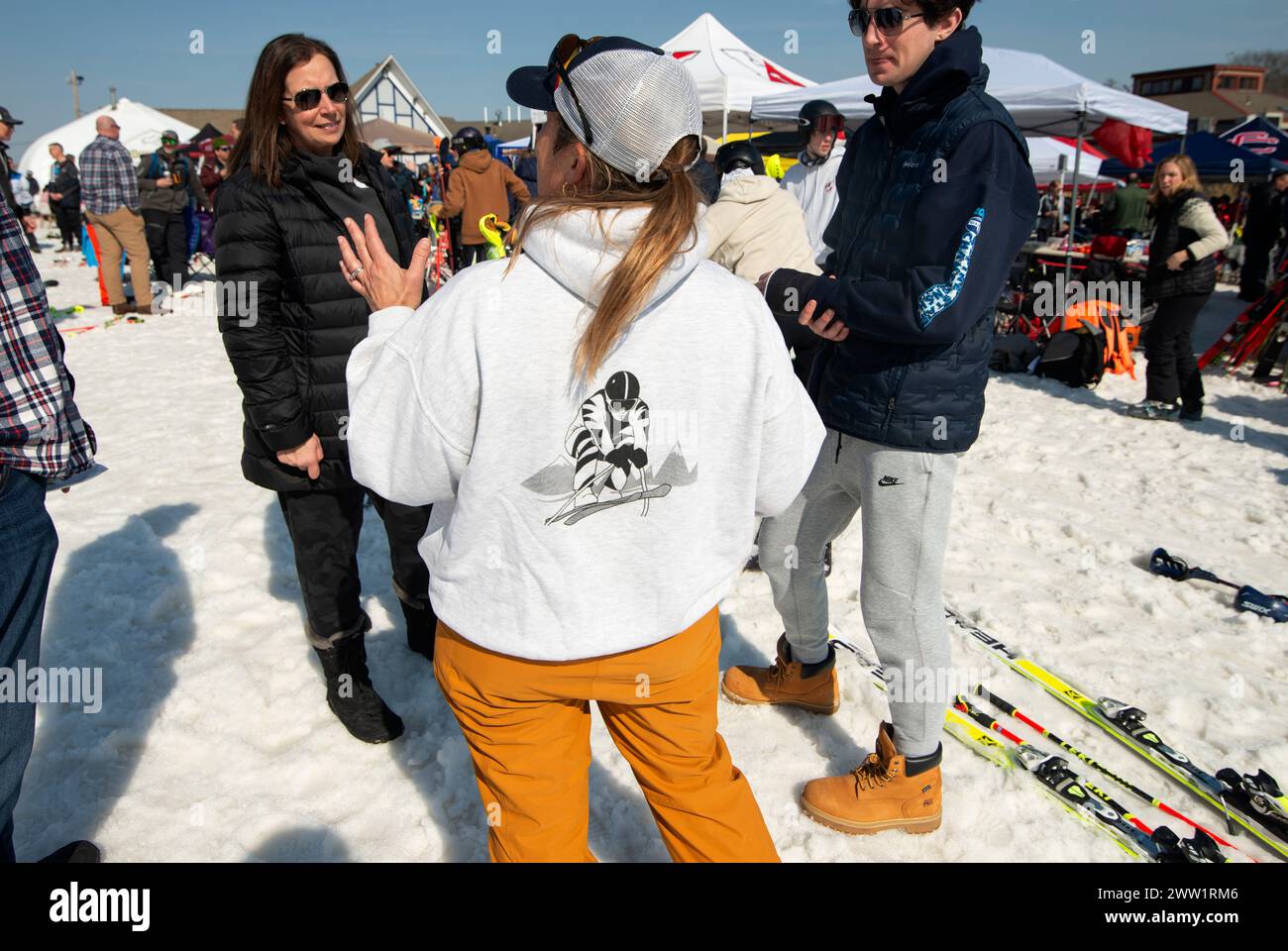 Massachusetts Interscholastic Athletic Association (MIAA) 2024 jährliche High School State Championship Slalom und Giant Slalom im Skigebiet Wachusett Mountain in Princeton, MA. Ein Teamtrainer, ein graues Sweatshirt mit einer Grafik des Skirennfahrers auf dem Rücken, spricht während des Rennens mit den Eltern. Stockfoto