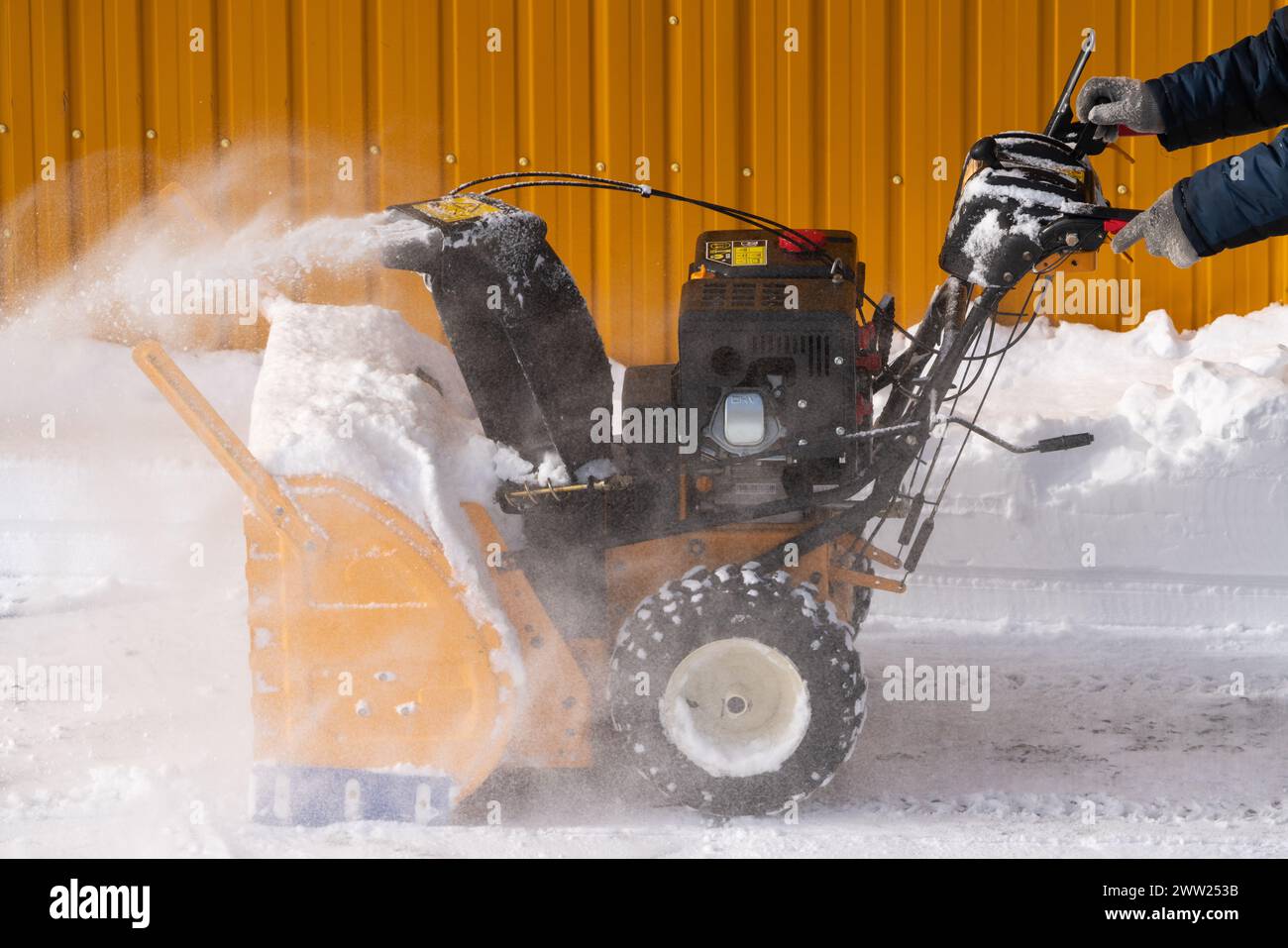 Mann mit Schneefräse, um Schnee nach Wintersturm zu entfernen. Er wird von einer Schneefräse auf einer Winterstraße unterstützt. Mann mit Schneefräse auf der Winterstraße Stockfoto