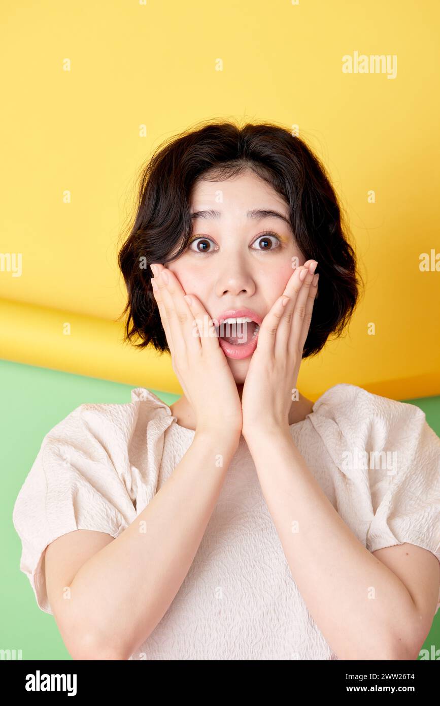 Asiatische Frau mit überraschtem Ausdruck auf buntem Hintergrund Stockfoto