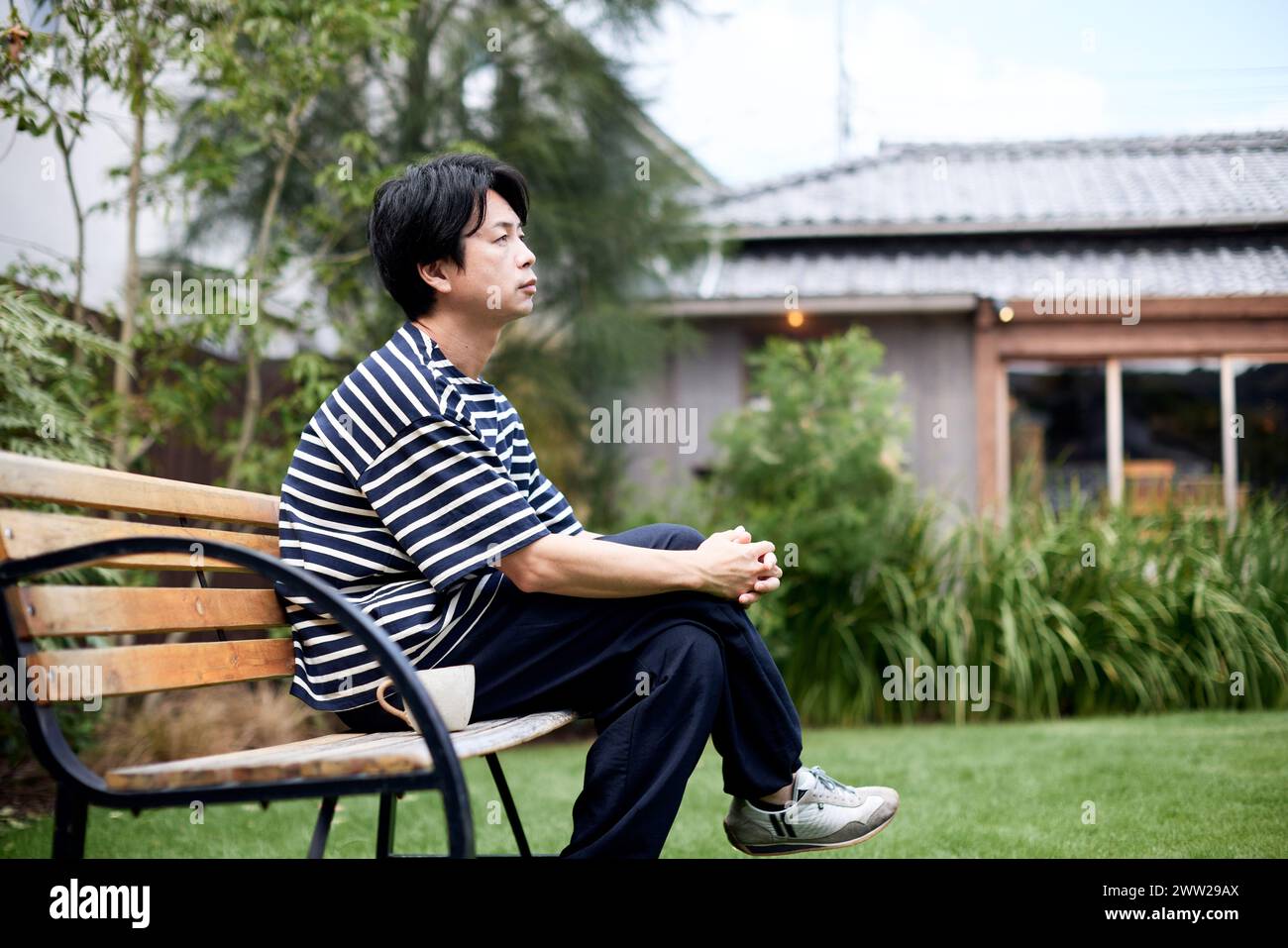 Ein Mann, der auf einer Bank im Garten sitzt Stockfoto