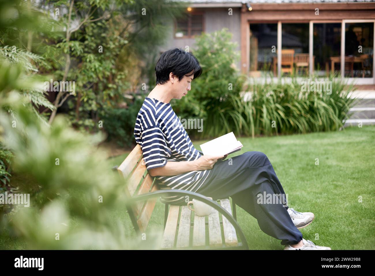 Ein Mann, der auf einer Bank sitzt und ein Buch liest Stockfoto