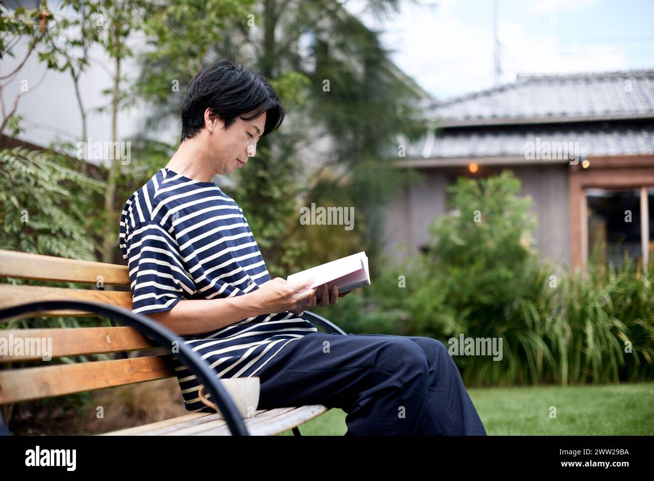Ein Mann, der auf einer Bank sitzt und ein Buch liest Stockfoto