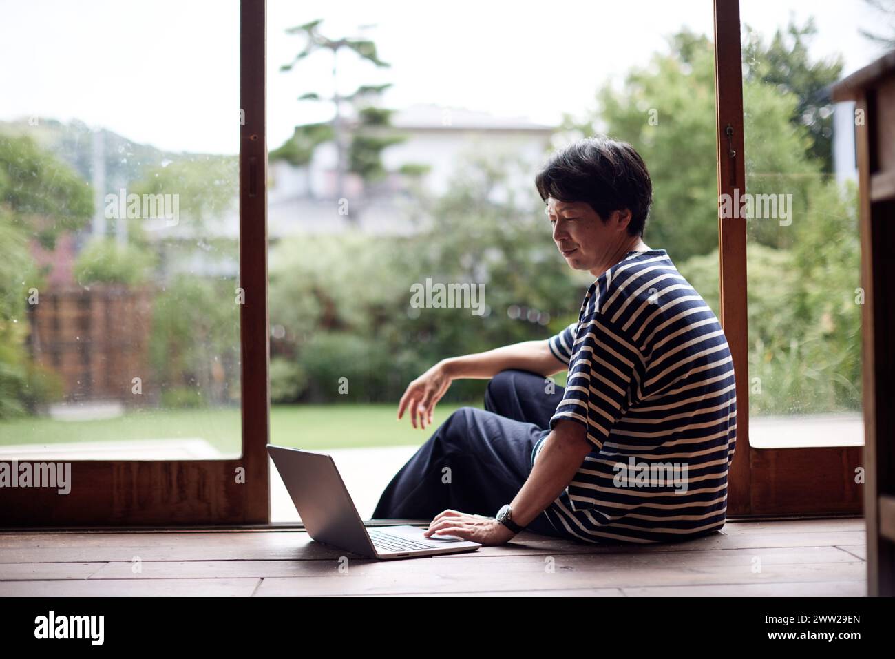 Ein Mann sitzt auf dem Boden mit einem Laptop Stockfoto