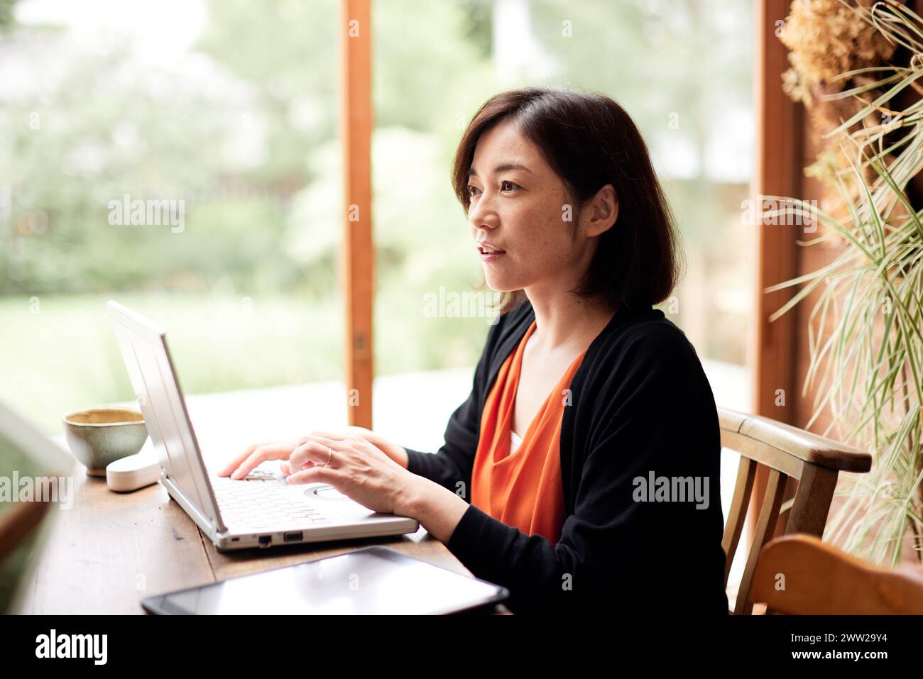 Eine Frau, die mit einem Laptop an einem Tisch sitzt Stockfoto