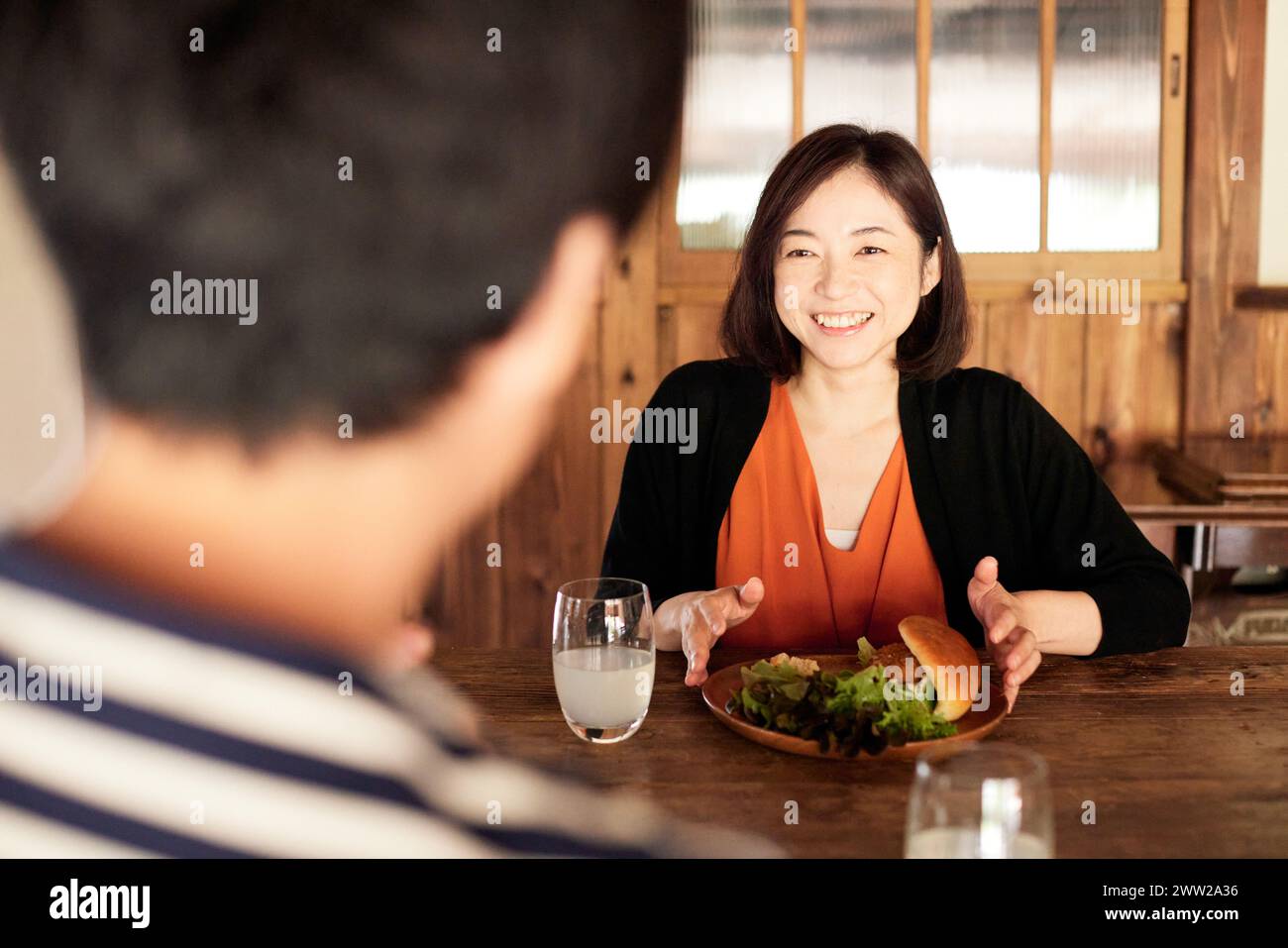 Eine Frau, die an einem Tisch sitzt, mit einem Sandwich und einem Glas Wasser Stockfoto