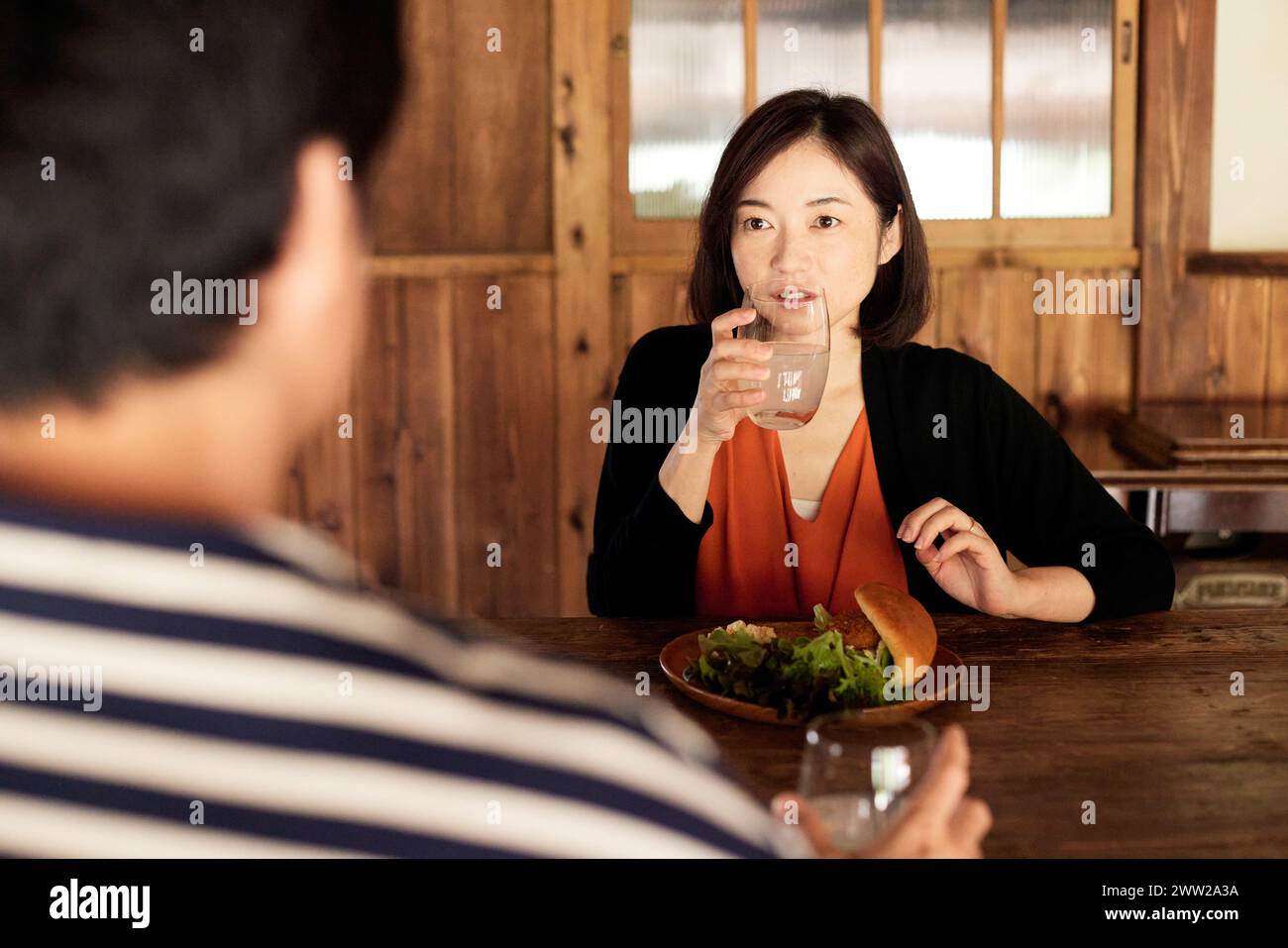 Eine Frau, die mit einem Teller Essen an einem Tisch sitzt Stockfoto