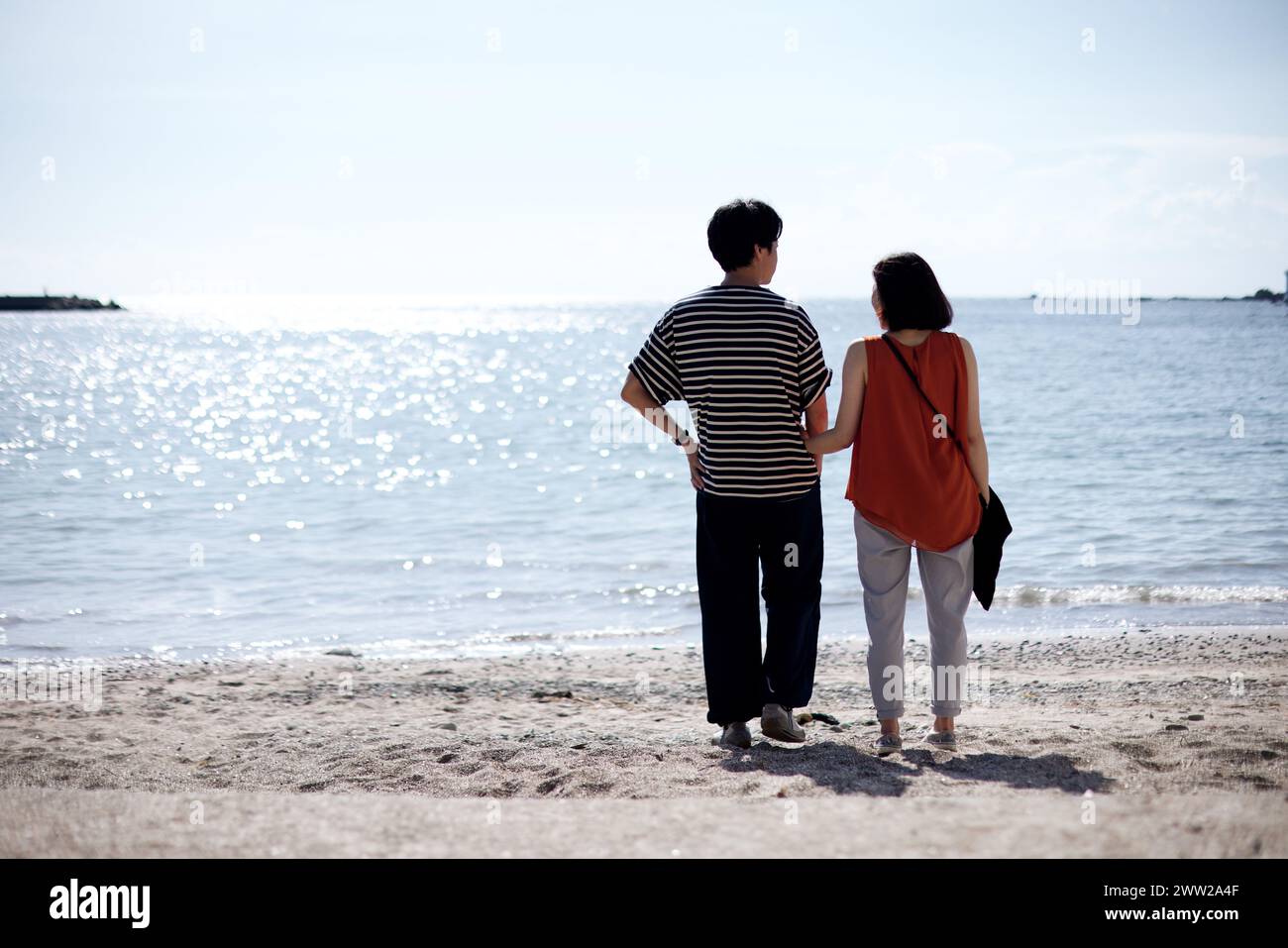 Ein Paar, das am Strand steht und auf das Meer blickt Stockfoto
