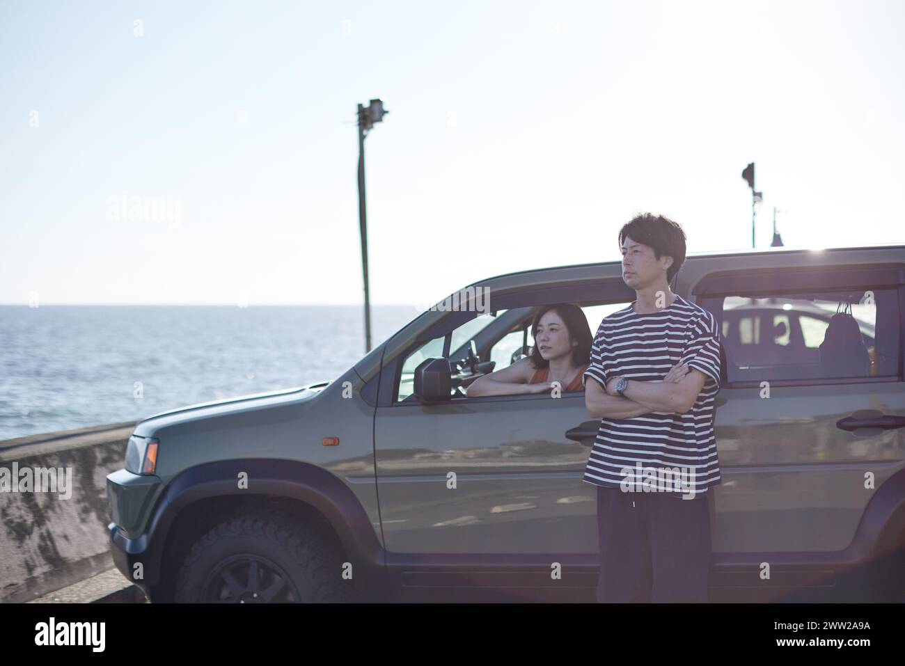Ein Mann und eine Frau stehen vor einem Auto am Meer Stockfoto