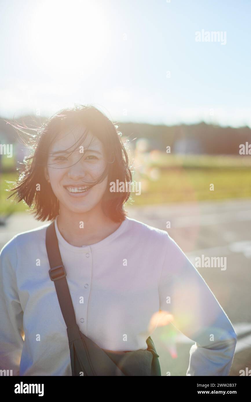 Eine Frau lächelt, während sie auf einer Straße steht Stockfoto