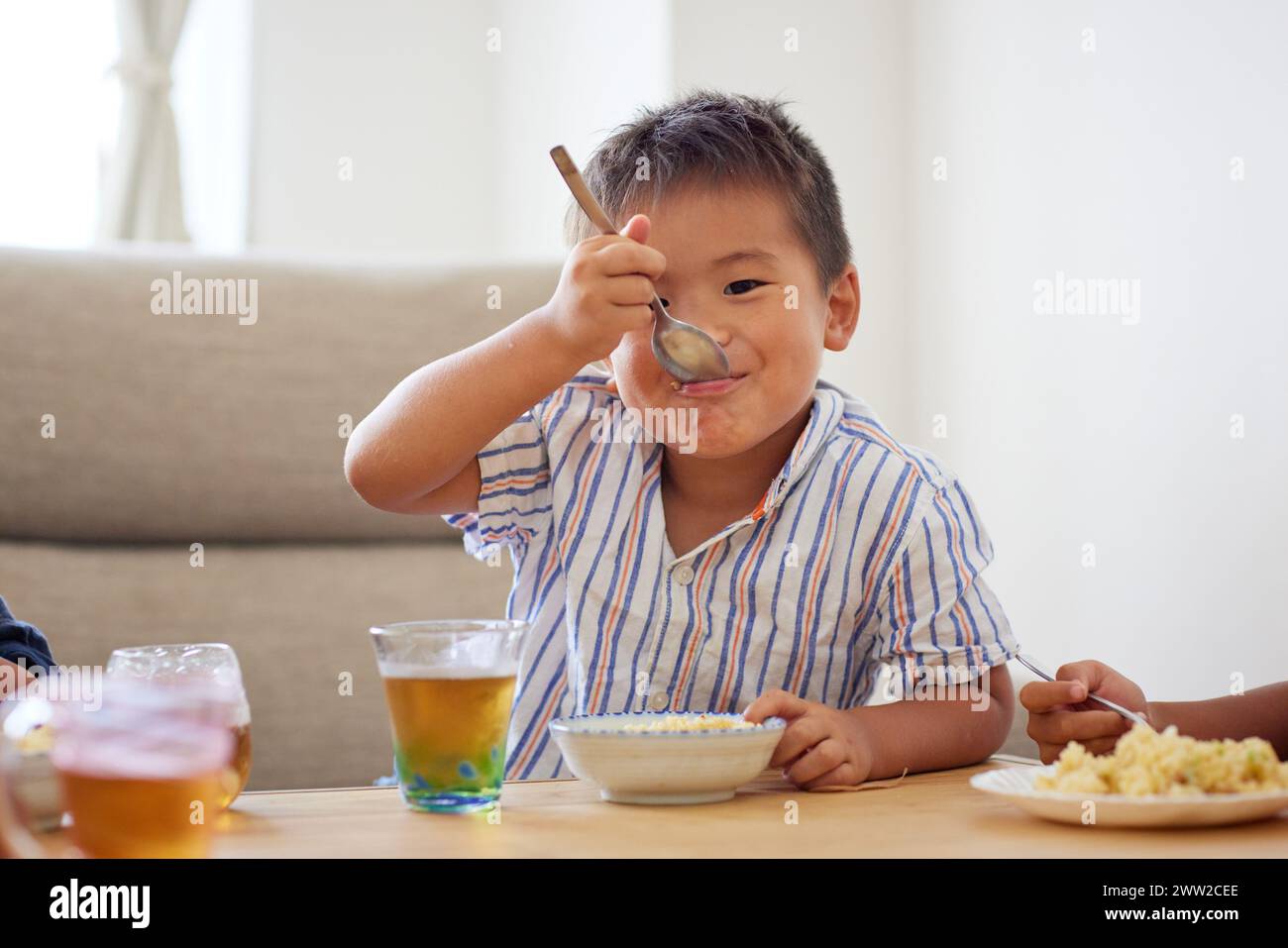 Junge, der an einem Tisch sitzt und Essen isst Stockfoto