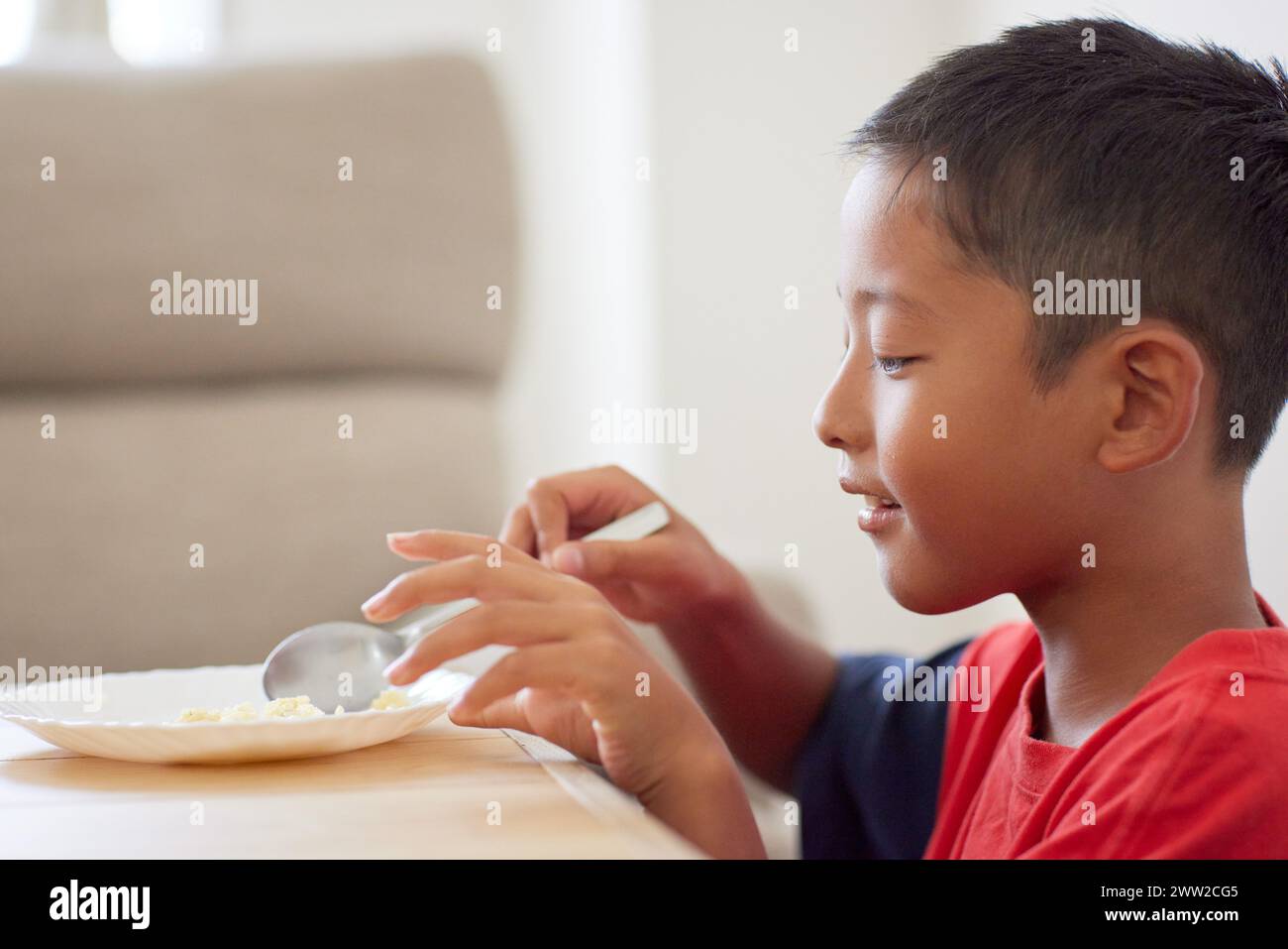 Junge, der an einem Tisch sitzt und Essen isst Stockfoto