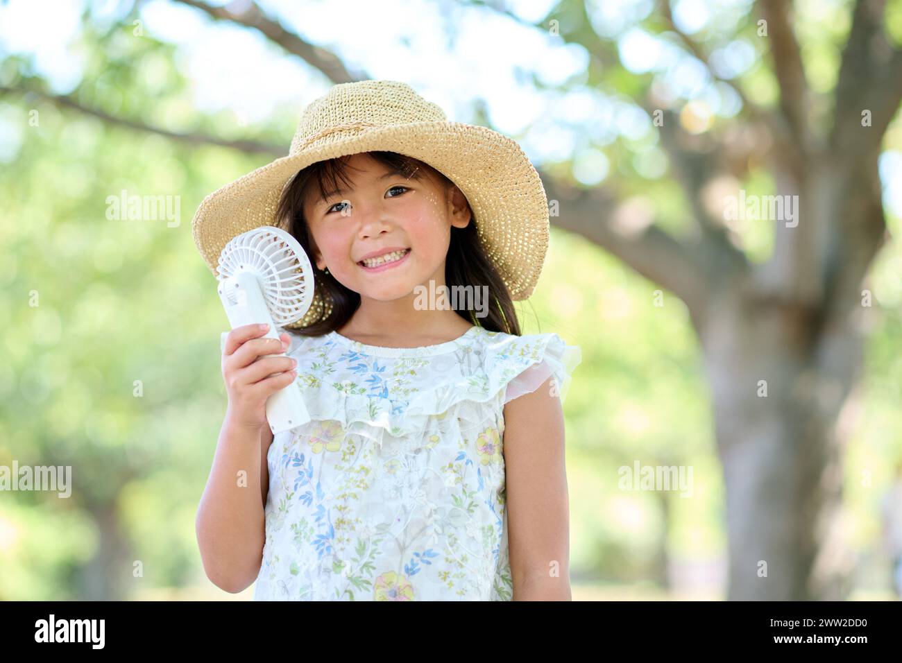 Ein junges Mädchen mit einem Hut, der einen Ventilator hält Stockfoto