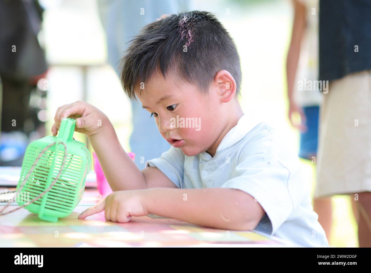 Ein kleiner Junge, der mit einem grünen Plastikspielzeug spielt Stockfoto