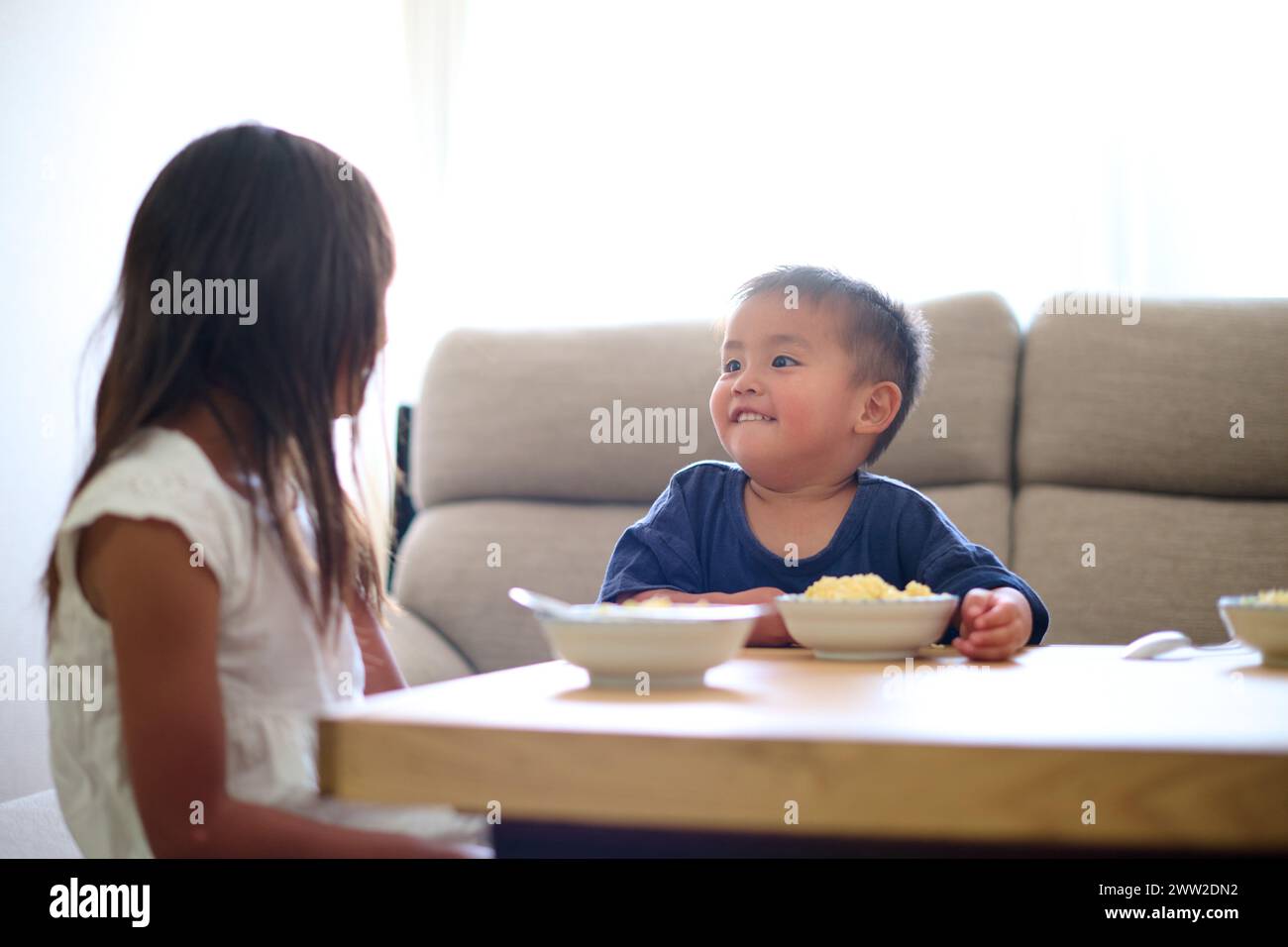 Kinder, die an einem Tisch sitzen und Essen essen Stockfoto