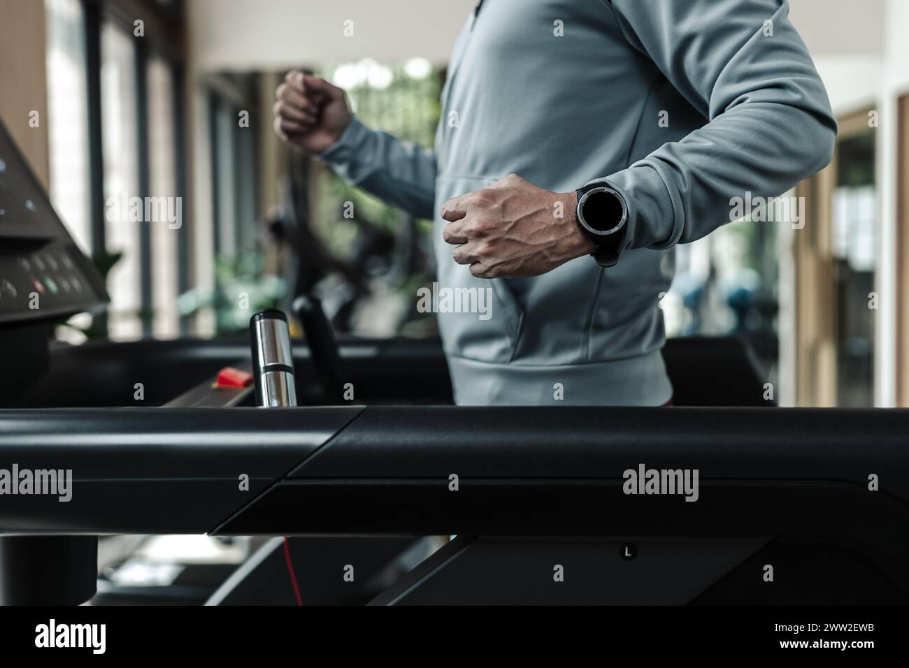 Ein Mann mit intelligenter Uhr, der auf dem Laufband läuft, Fitness treibt. Fitness, Fitnessstudio, Workout und Lifestyle-Konzept. Stockfoto