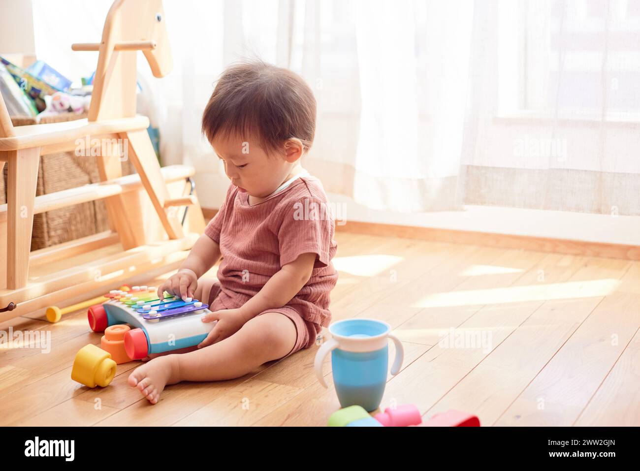 Ein Kleinkind, das mit Spielzeug auf dem Boden spielt Stockfoto