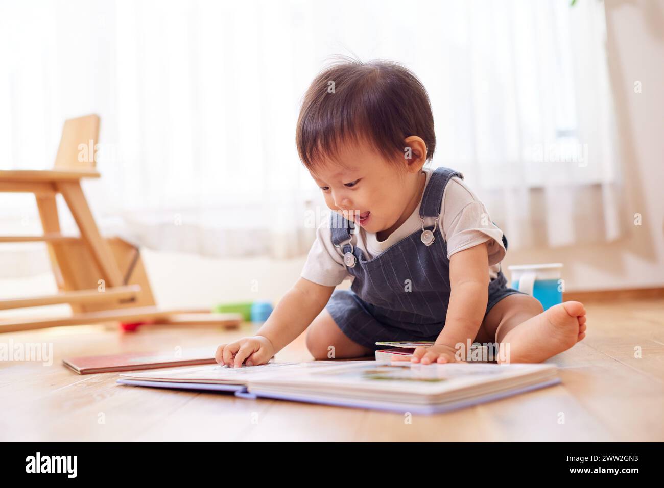 Ein Baby, das mit einem Buch auf dem Boden spielt Stockfoto