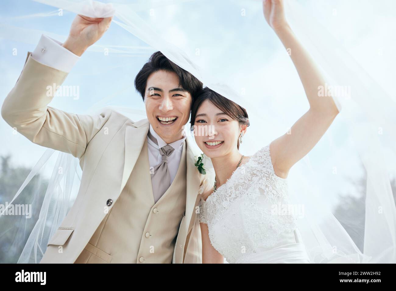 Braut und Bräutigam halten einen Schleier hoch Stockfoto