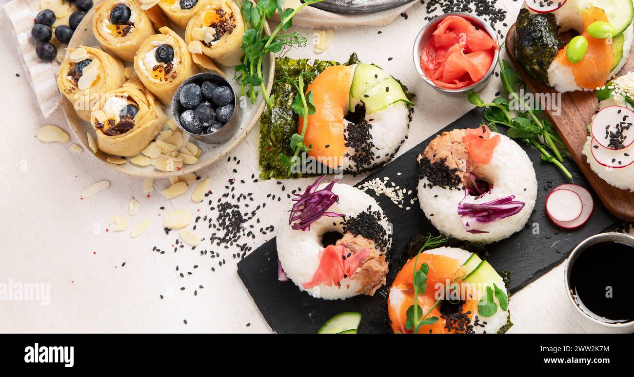 Trend-Hybridfutter. Japanische asiatische Küche. Sushi-Donuts, süße Sushi-Pfannkuchen und Saucen auf hellem Hintergrund. Draufsicht. Stockfoto