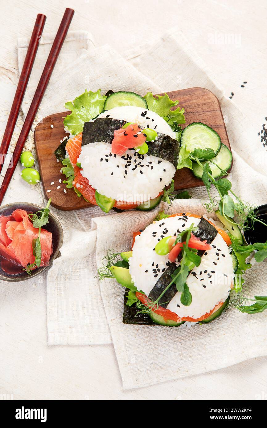 Moderne Hybridkost. Sushi-Burger mit Lachs, weißem Reis, Avocado, Gurke. Draufsicht Stockfoto