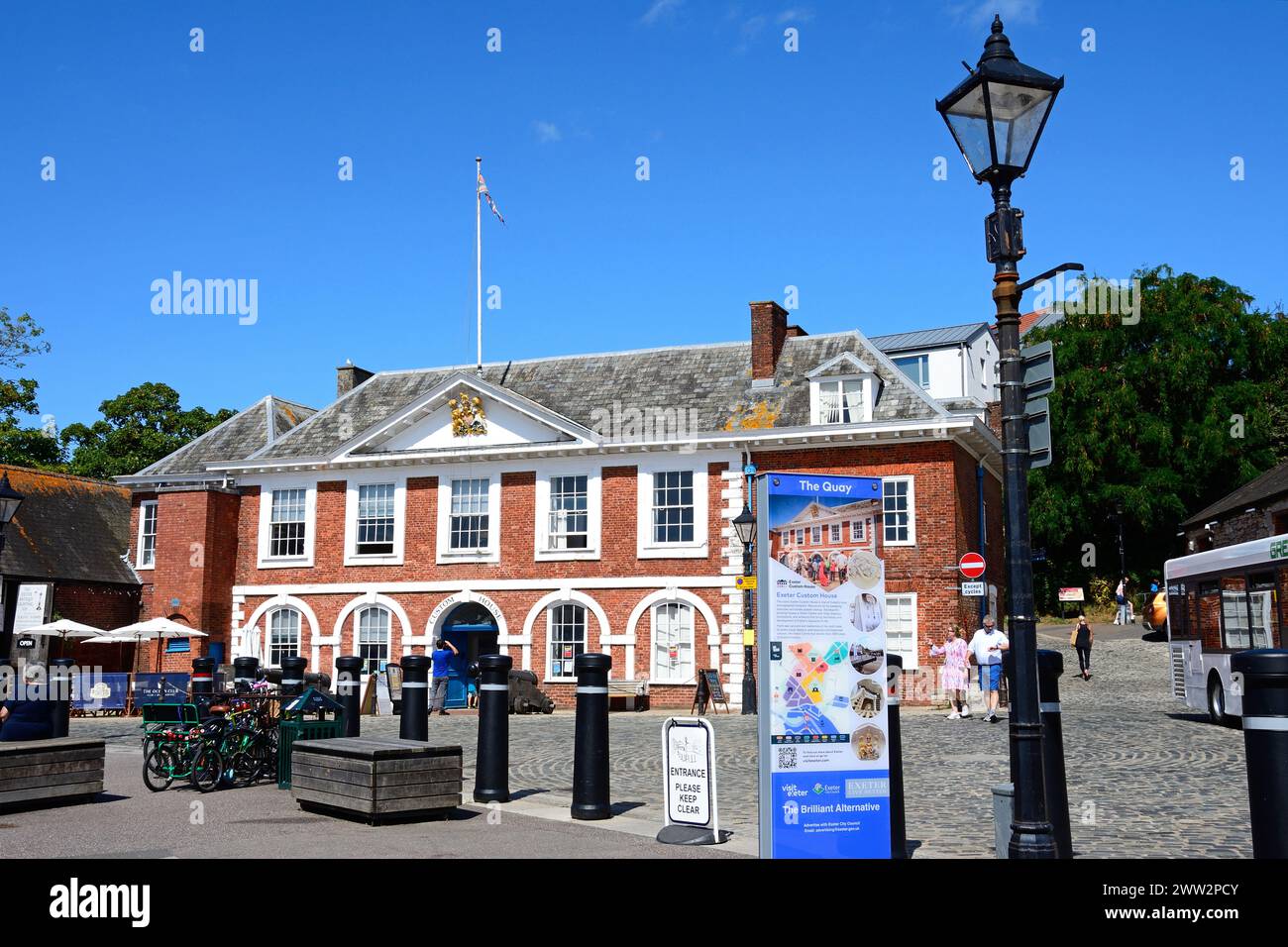 Vorderansicht des Custom House (heute ein Besucherzentrum) entlang der Uferpromenade mit einem Informationsschild im Vordergrund, Exeter, Devon, Großbritannien. Stockfoto