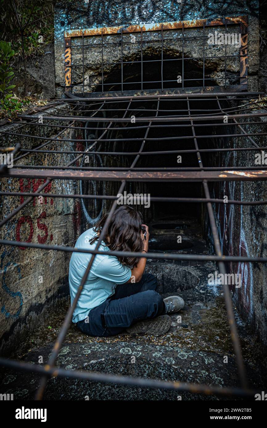 Ein Stadtforscher fängt das Geheimnis eines graffierten Tunnels hinter einem Metallgitter ein. Stockfoto