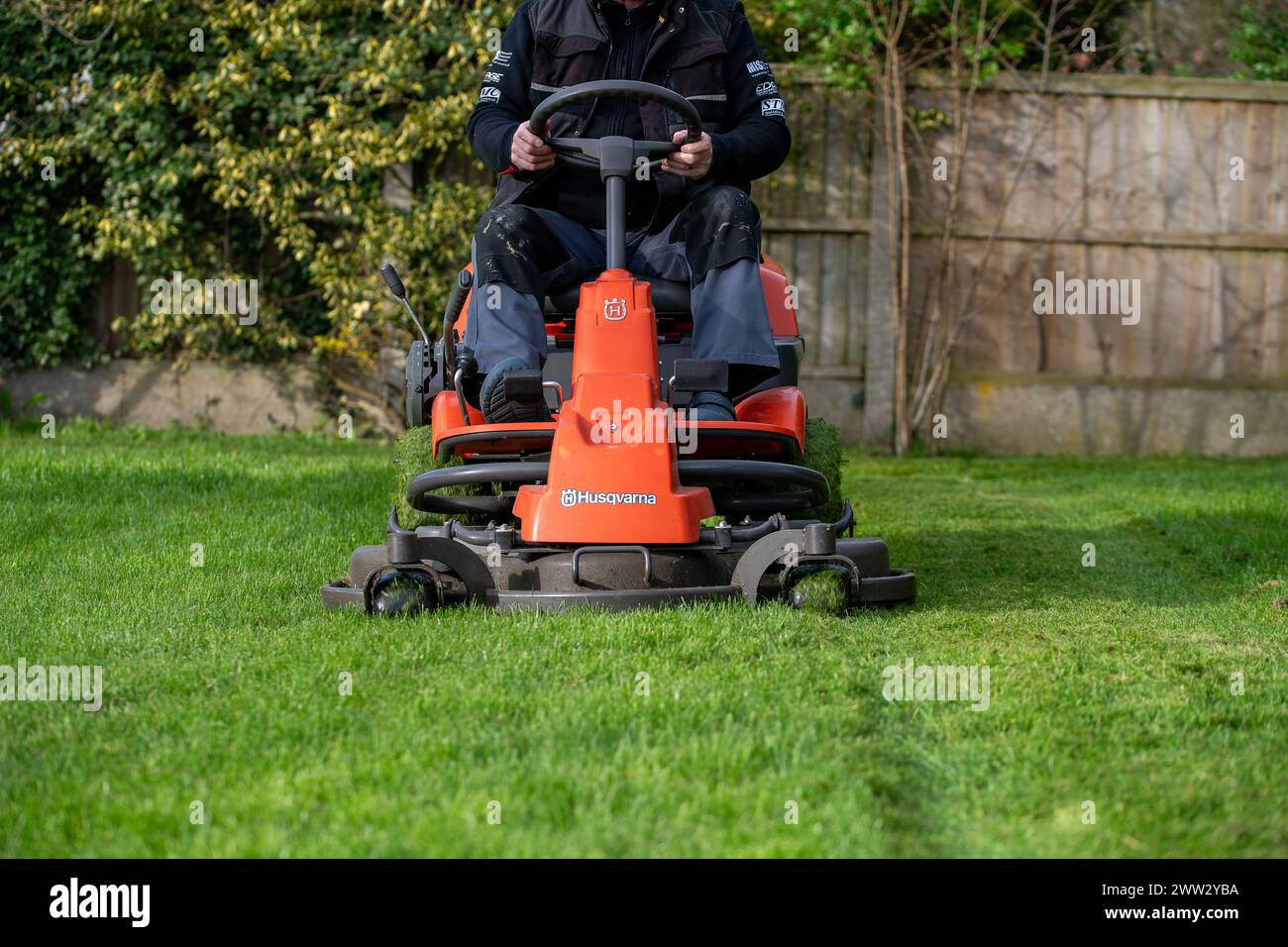 Ein Mann, der auf dem Rasenmäher einen Rasen mäht Stockfoto