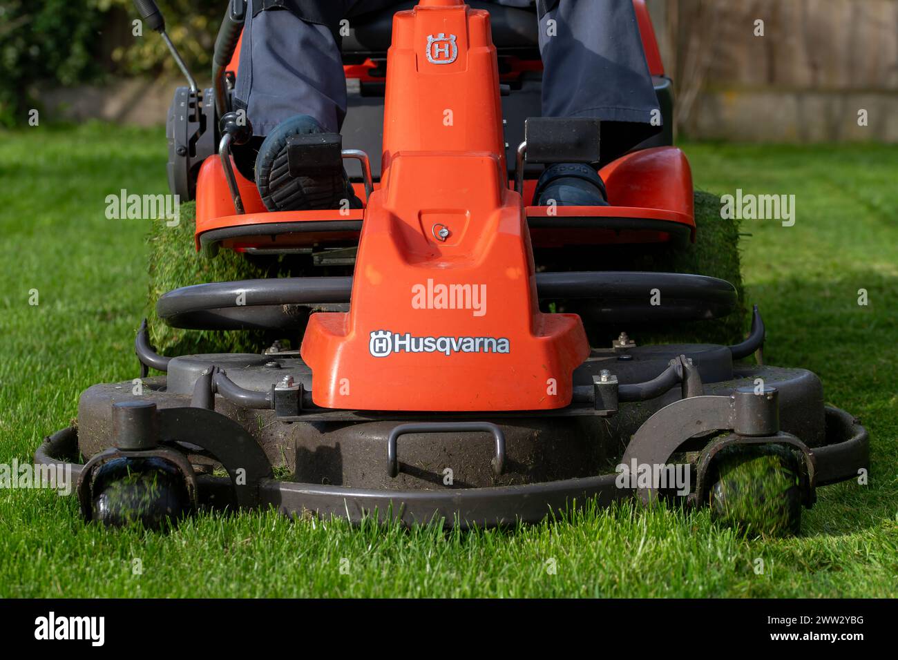 Ein Mann, der auf dem Rasenmäher einen Rasen mäht Stockfoto