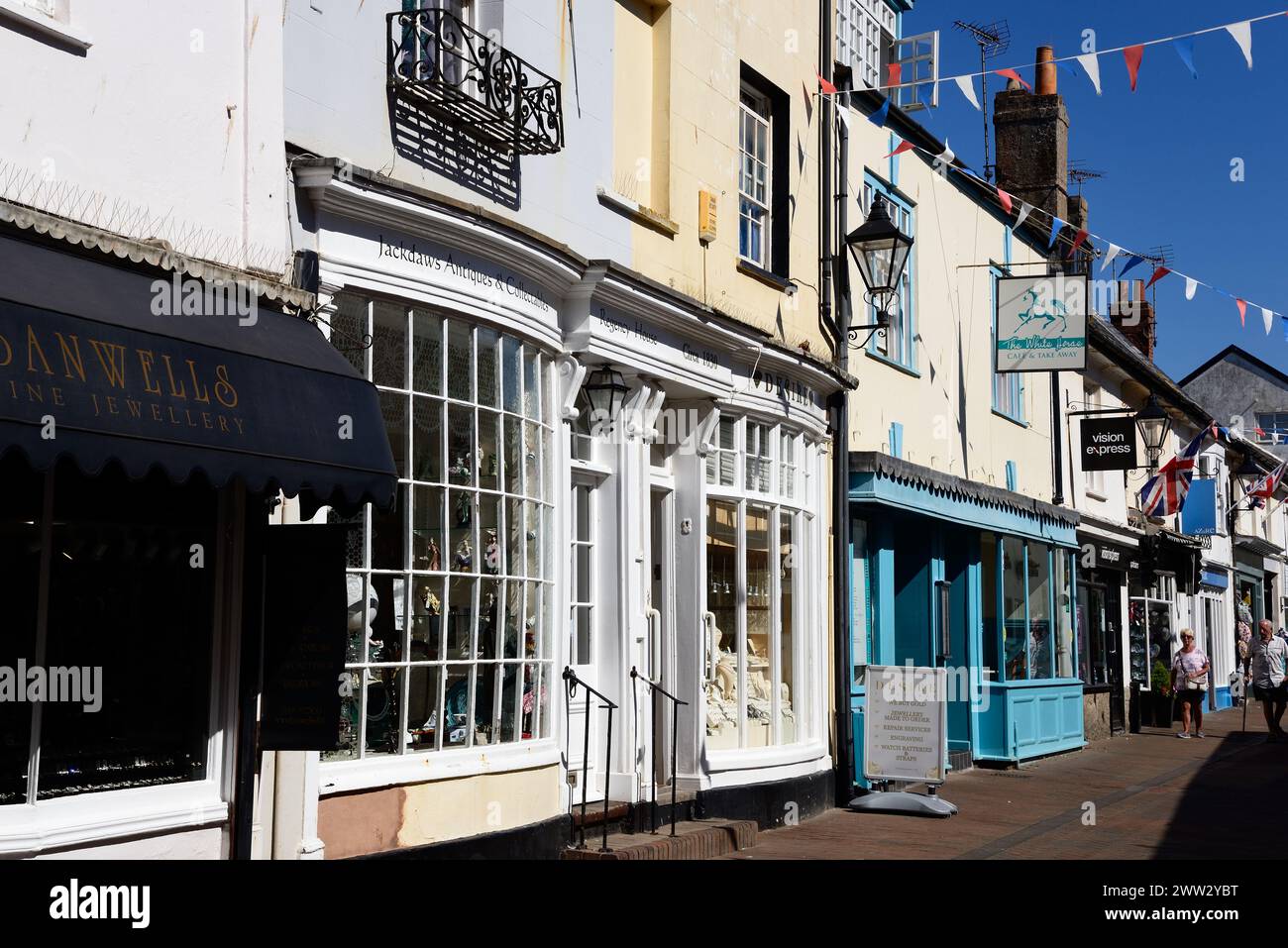 Shoppers und Shops entlang der Old Fore Street im Stadtzentrum, Sidmouth, Devon, Großbritannien, Europa. Stockfoto
