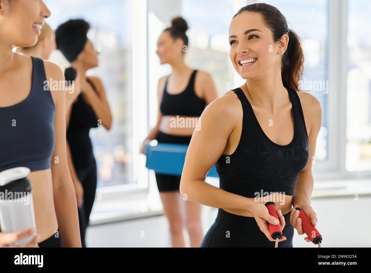 Glückliche multikulturelle Freundinnen in aktiver Kleidung, die sich nach dem Pilates-Workout gegenseitig anlächeln Stockfoto
