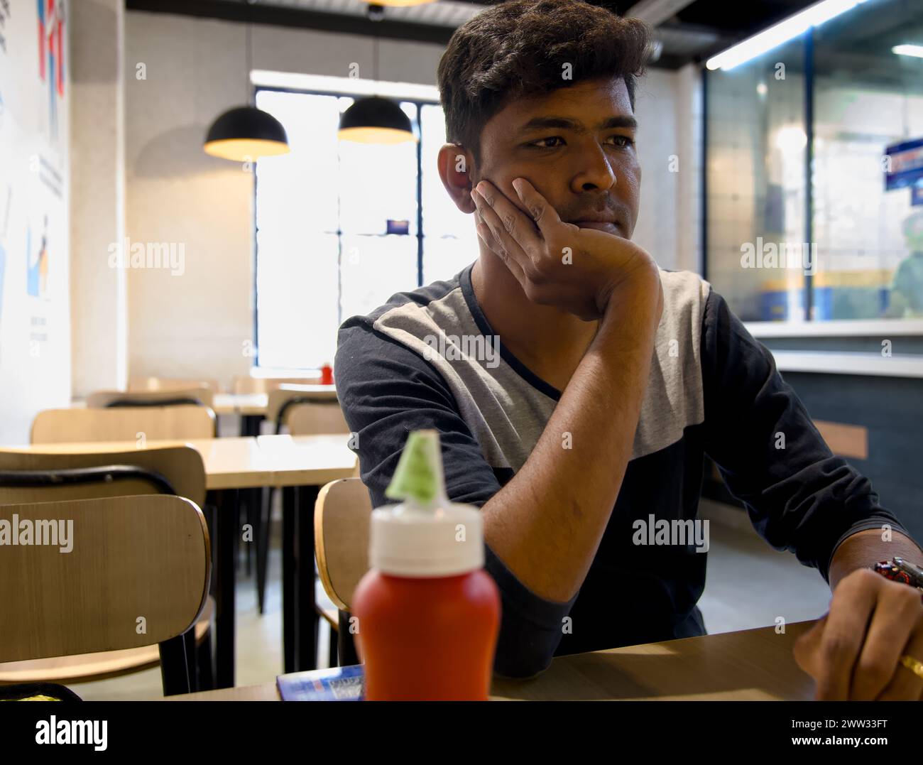 Ein junger Mann denkt über das Leben mit einer Stirnrunze nach, während er sich klammert Stockfoto