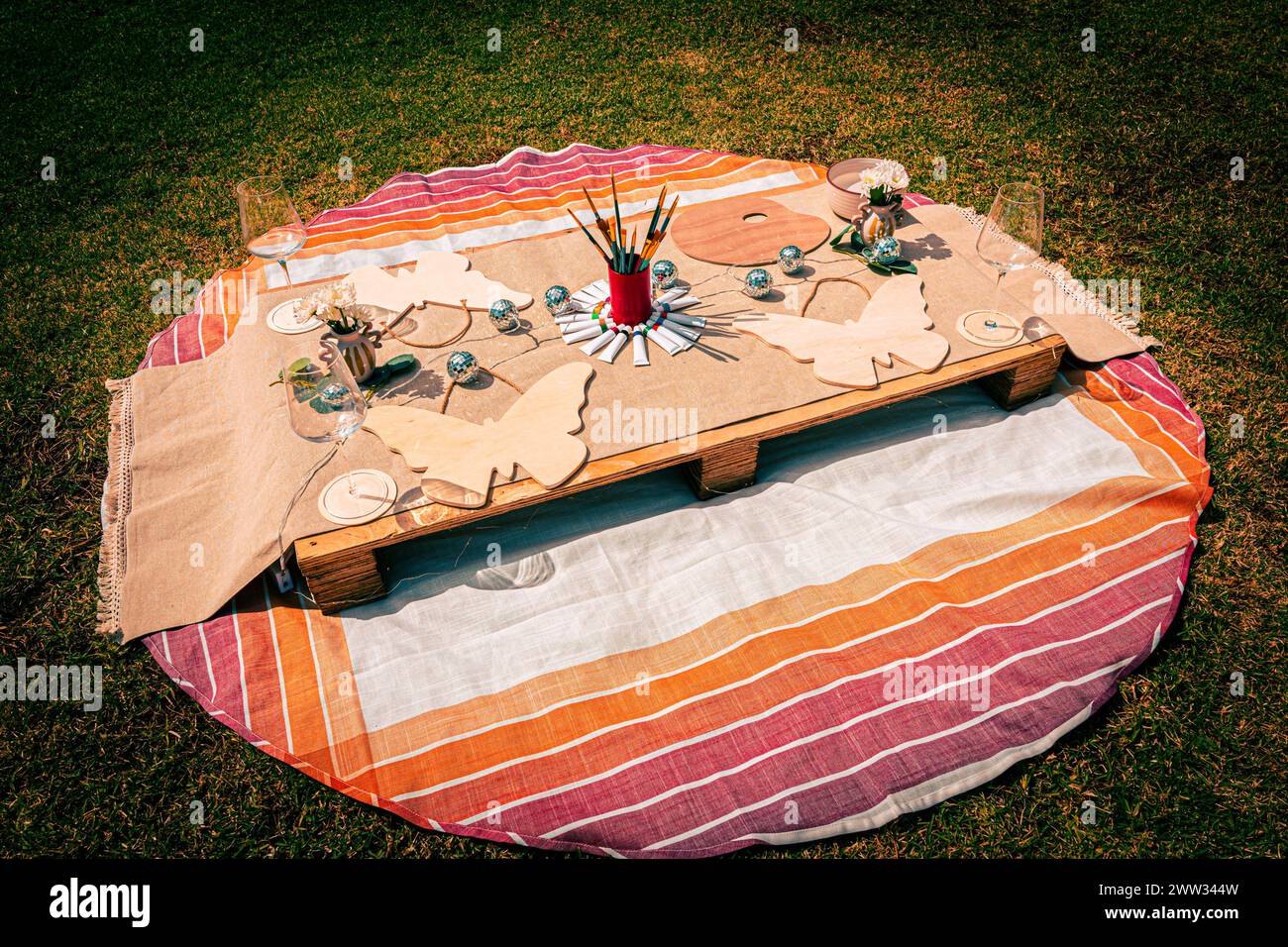 Top-Down-Aufnahme eines böhmischen Picknicks mit Kunst- und Essensgegenständen auf Gras. Stockfoto