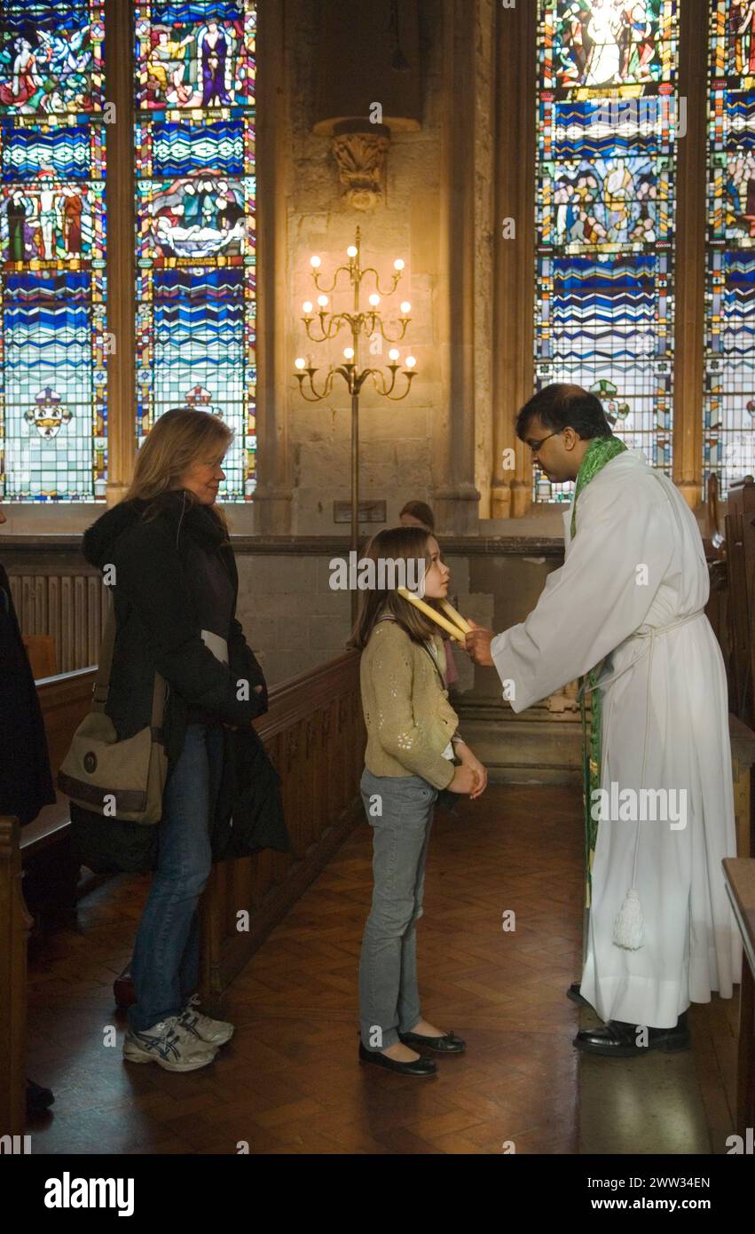 Das junge katholische Mädchen und ihre Mutter stehen an, um vom römisch-katholischen Priester gesegnet zu werden, in einem jährlichen katholischen Ritual der Zeremonie zum Segen der Kehle am 3. Februar Kerzen werden an beiden Seiten der Kehle platziert. Die katholische Kirche St. Etheldreda. Ely Place London. HOMER SYKES AUS DEN 2000ER JAHREN Stockfoto