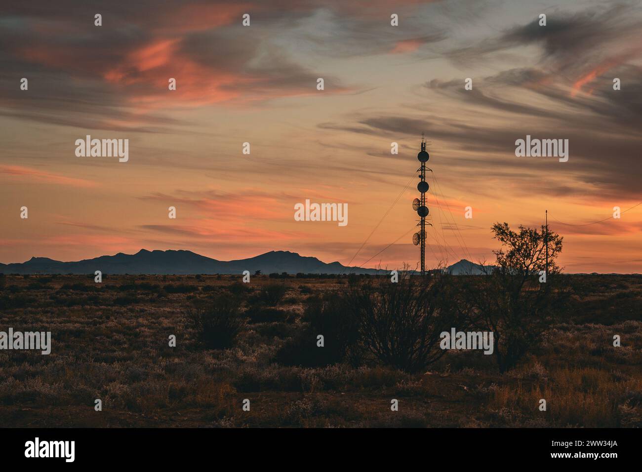 Die Silhouette der Kommunikationstürme hebt sich von einem feurigen Sonnenuntergangshimmel ab. Stockfoto