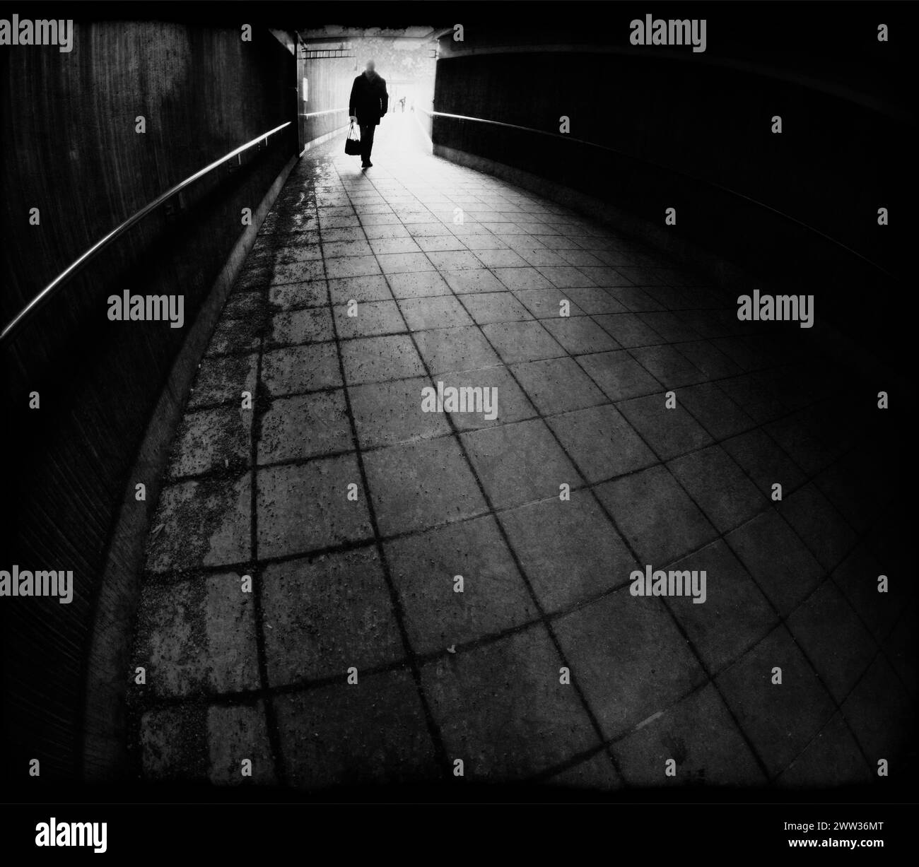 Silhouette eines Mannes, der in einen dunklen Tunnel eindringt, in Schwarz-weiß Stockfoto