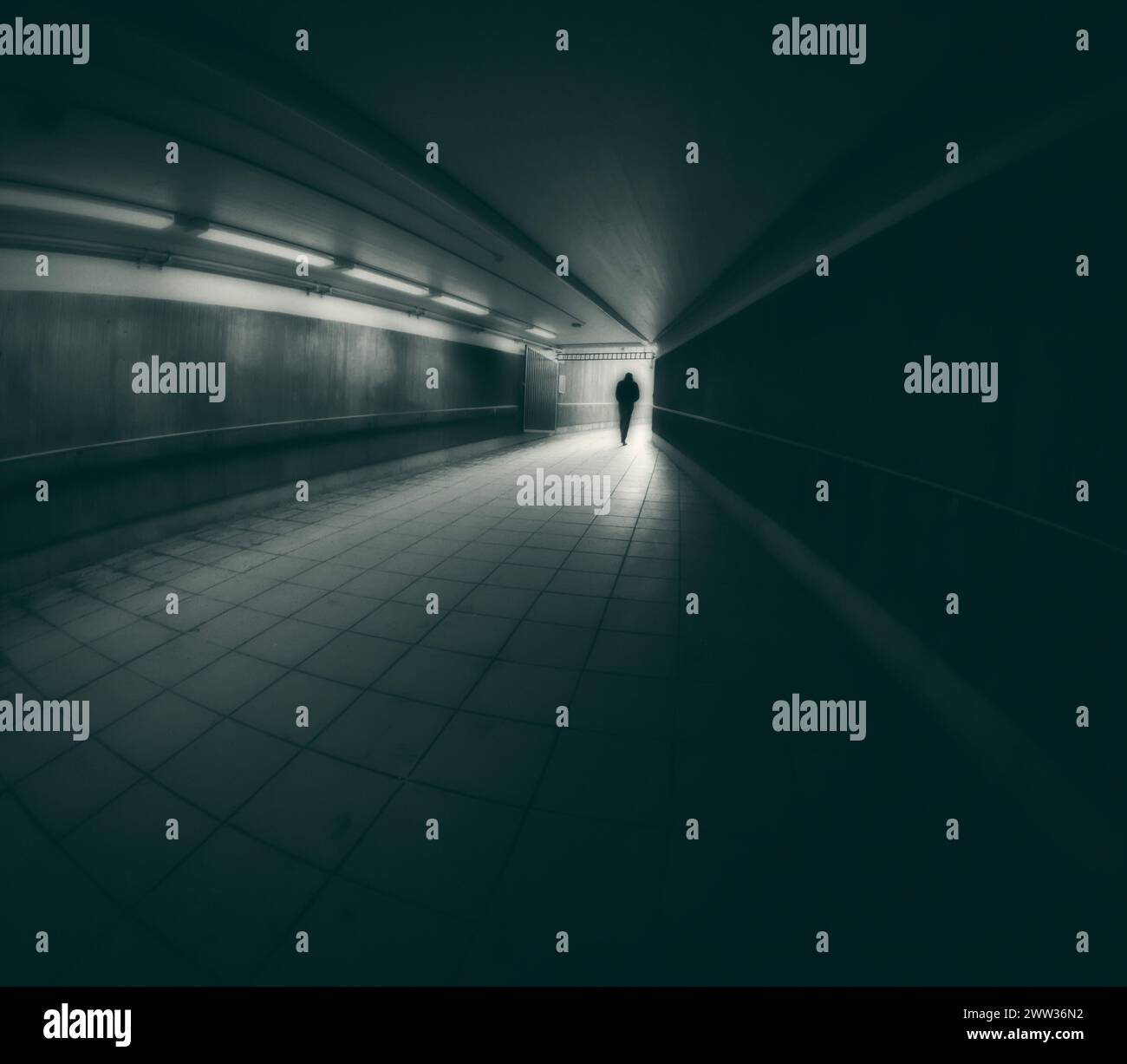 Kreatives traumhaftes Bild eines einsamen jungen Menschen, der in einem Tunnel auf das Licht zugeht. Stockfoto