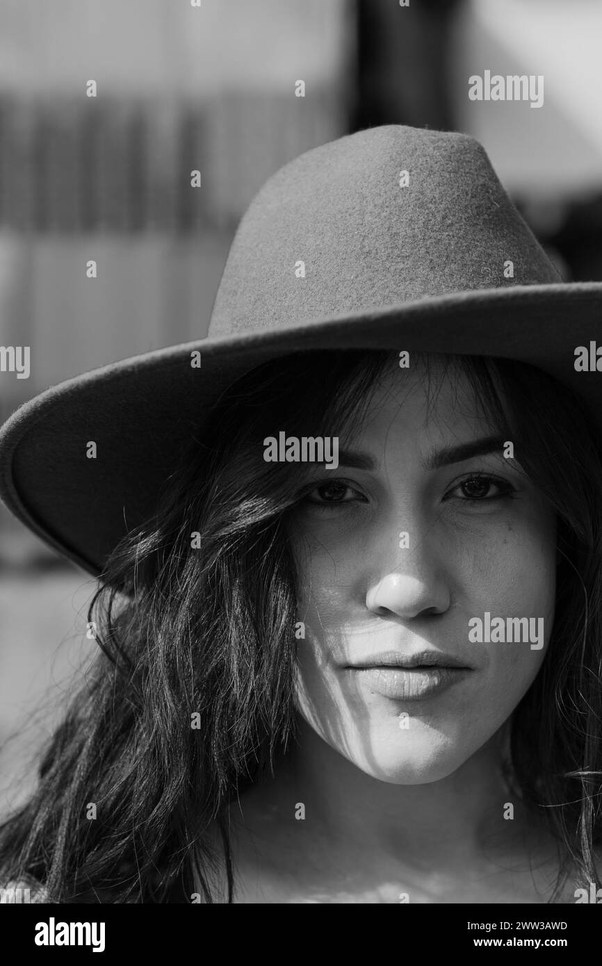 Monochromes Nahporträt einer spanischen jungen Frau mit schwarzem Hut, die ruhig nach vorne blickt Stockfoto