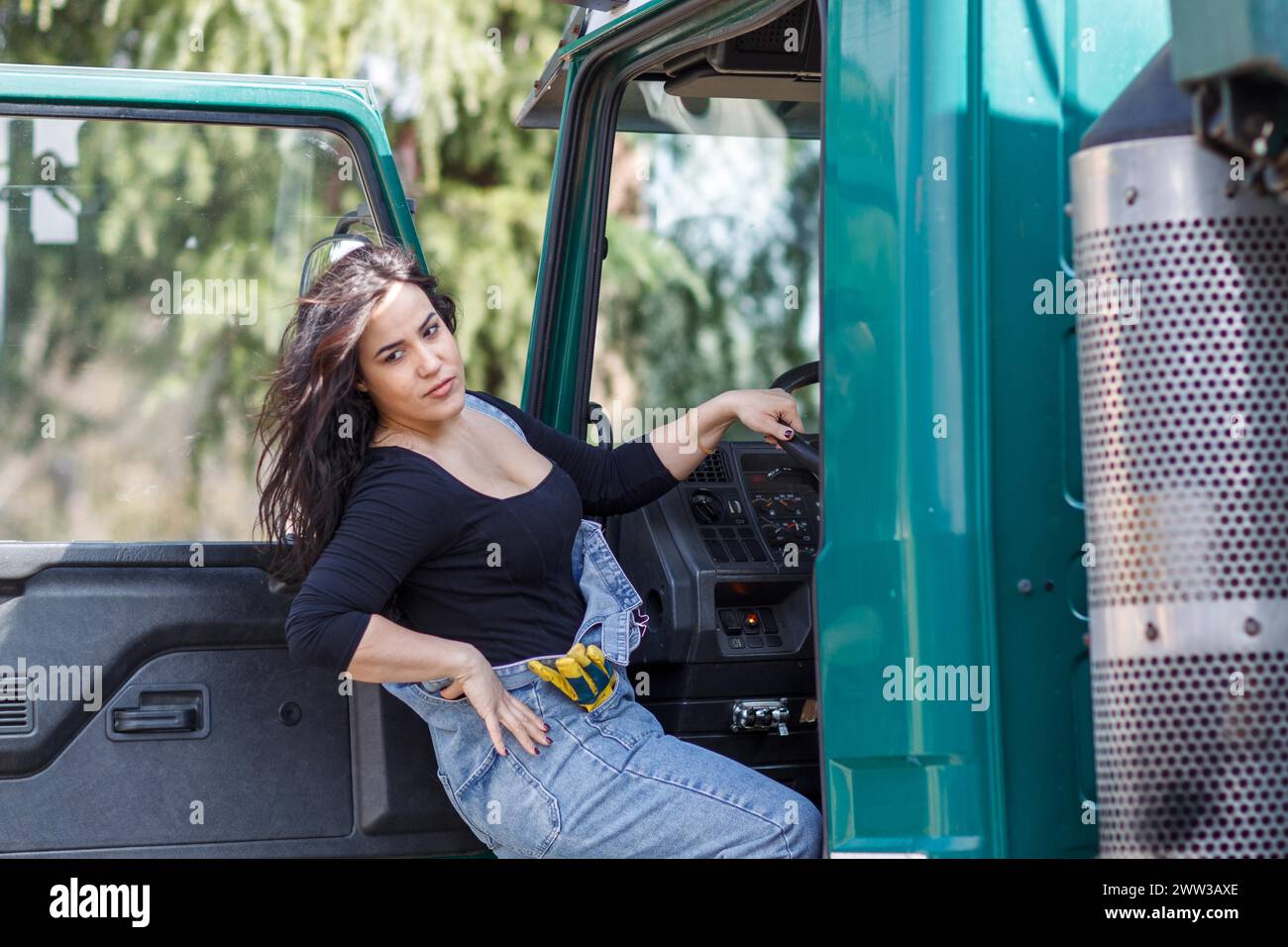 Selbstbewusste Frau posiert auf dem Fahrersitz des Lkws mit Hand am Lenkrad Stockfoto