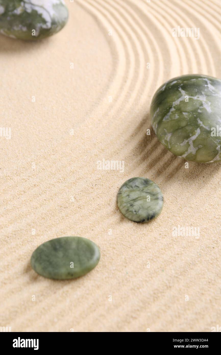 Zen-Gartensteine auf beigem Sand mit Muster Stockfoto