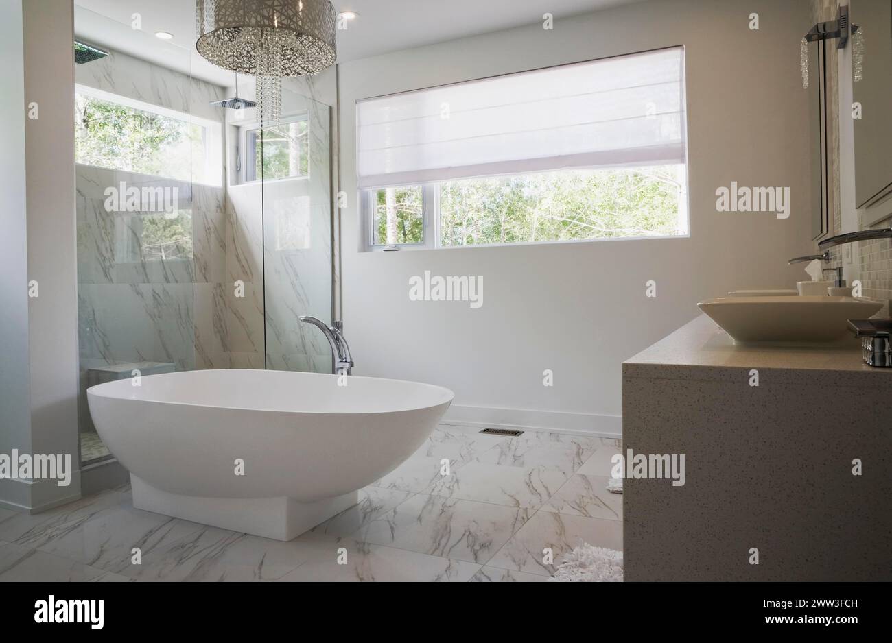 Glasdusche mit weißer freistehender Badewanne aus Acryl im Hauptbadezimmer mit Marmorfliesen im luxuriösen Haus, Quebec, Kanada Stockfoto