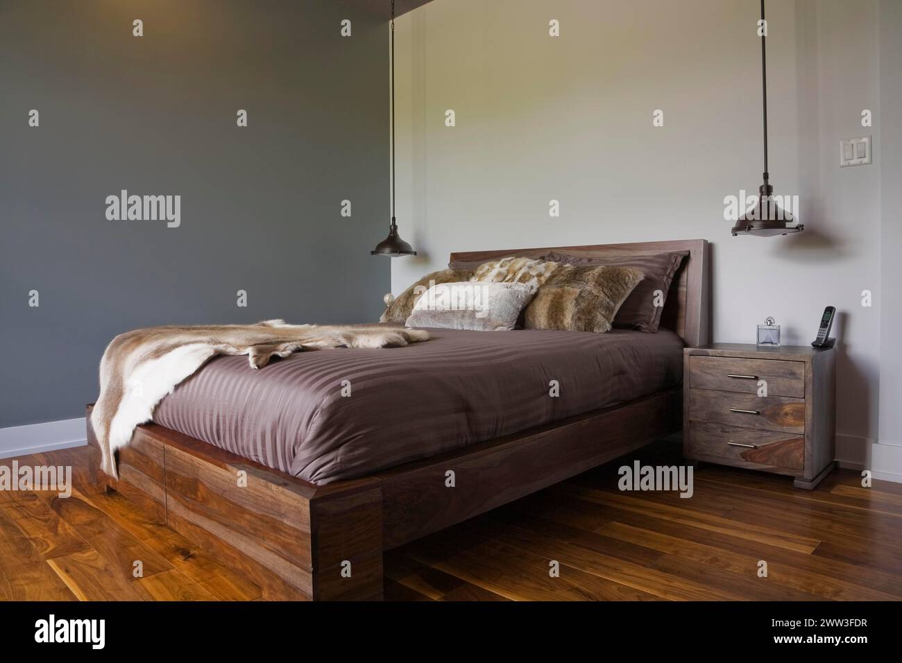 Queen-Size-hölzernes Fußbett mit Pelzpelzüberwurf im Gästezimmer im luxuriösen Haus, Quebec, Kanada Stockfoto