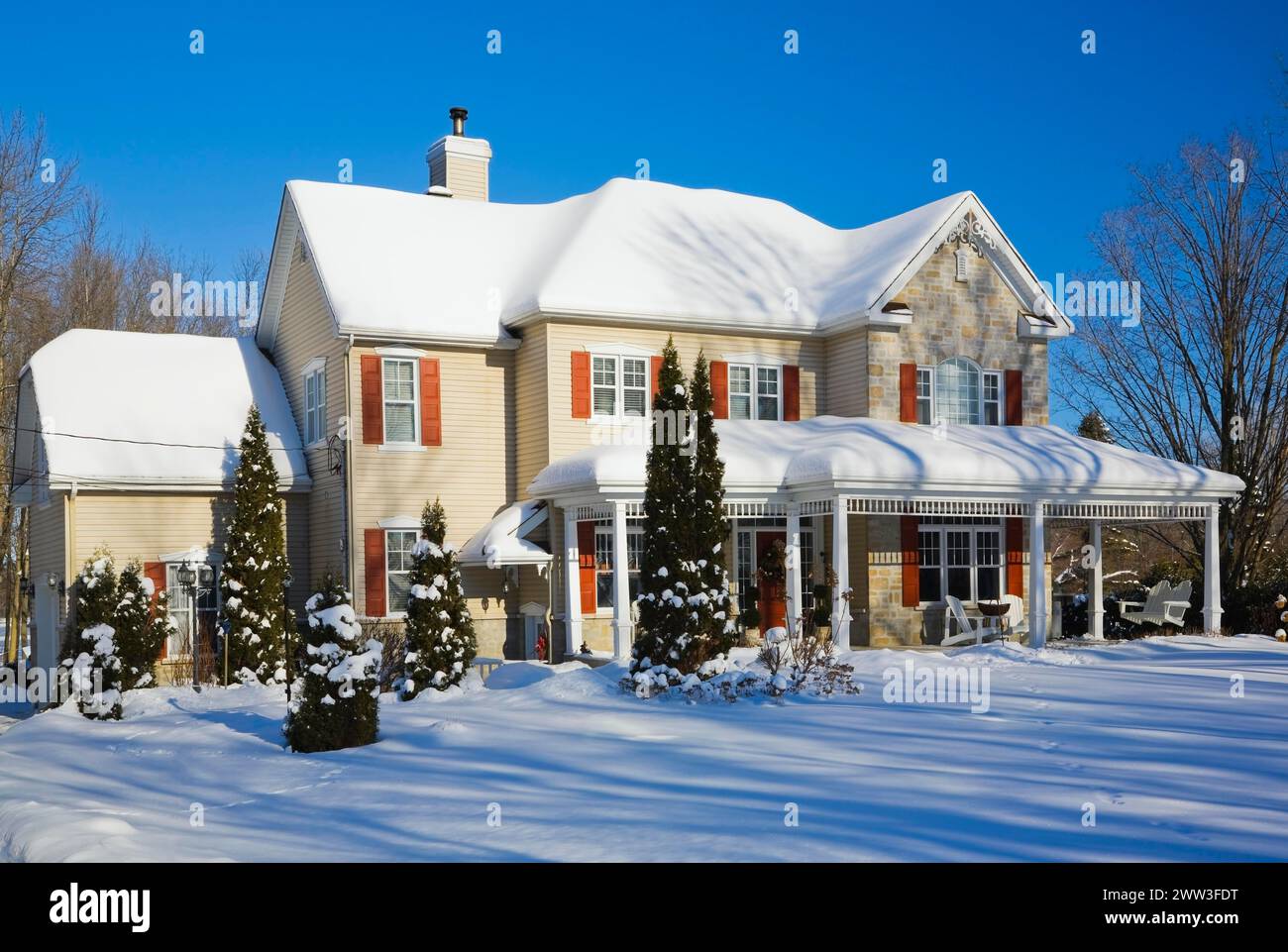 Zweistöckiges beigefarbenes Vinyl-Nebengebäude mit bräunlich-roten Ziegel-Furnier und orangefarbenen Zierleisten im Winter in Quebec, Kanada Stockfoto