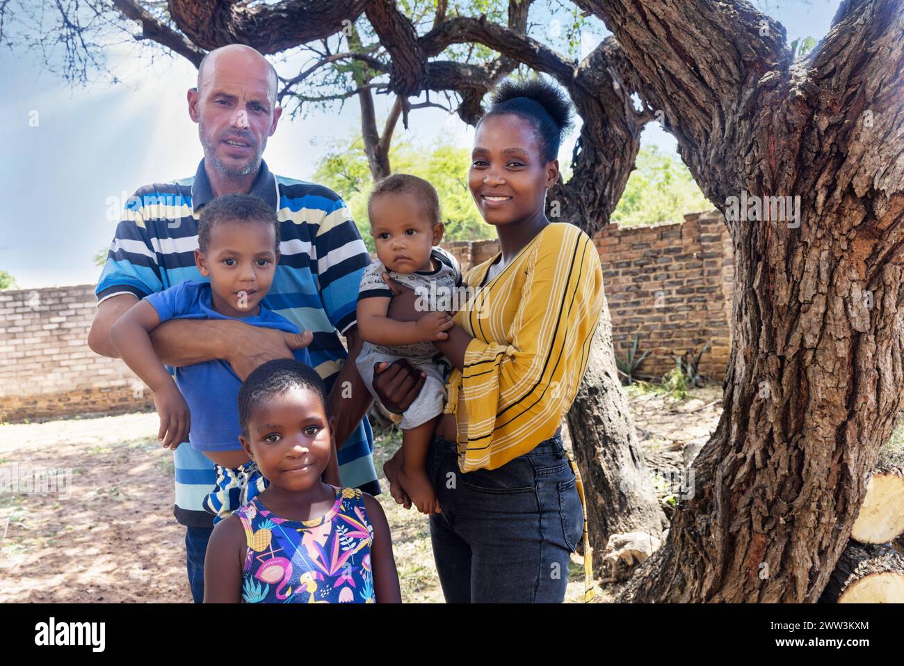 afrikanische Familie mit drei Kindern, die im Hinterhof stehen, in der Gemeinde, am späten Nachmittag, Stockfoto