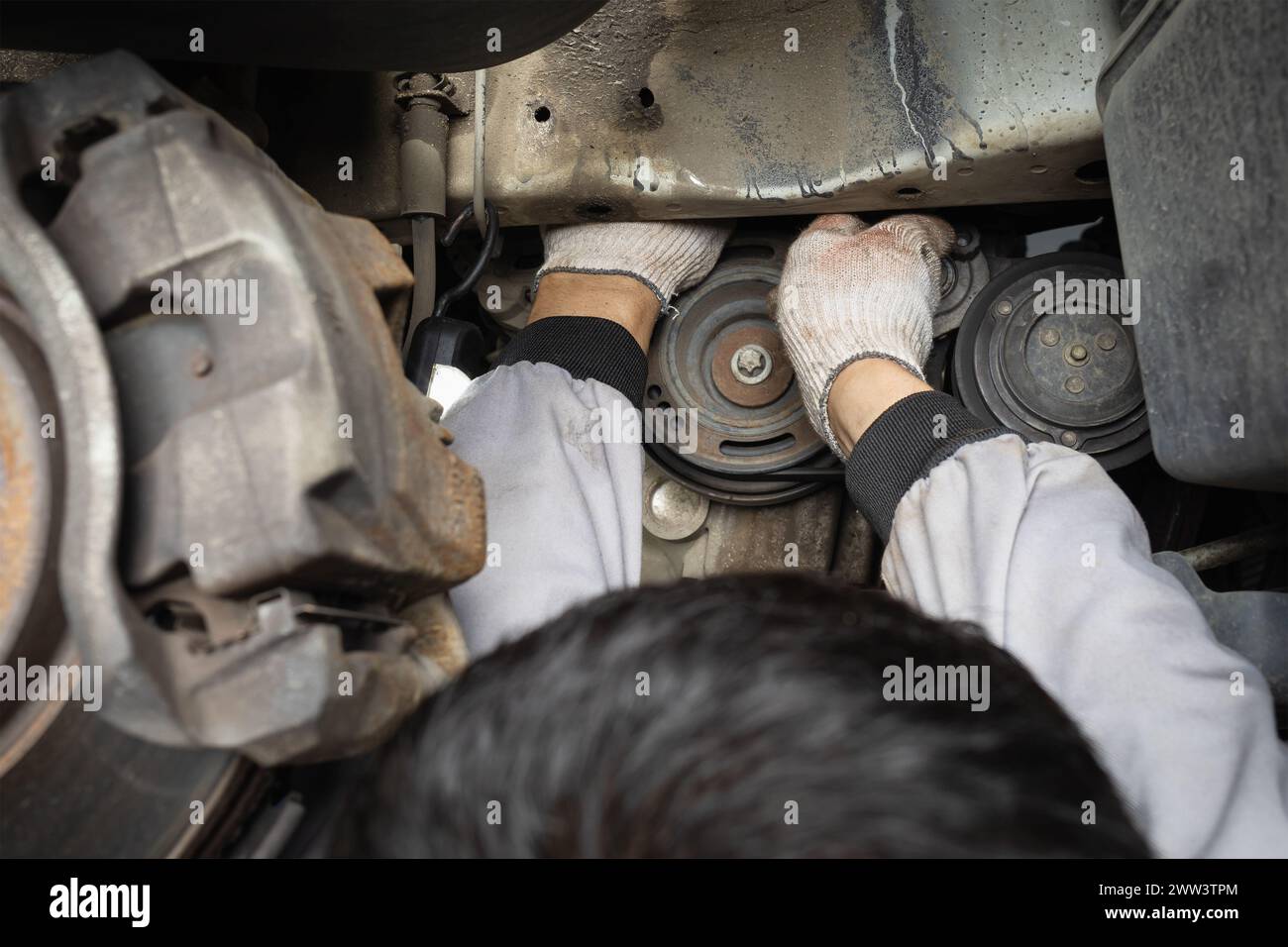 Ein Mechaniker entfernt während der Fahrzeugwartung verschiedene Riemen Stockfoto