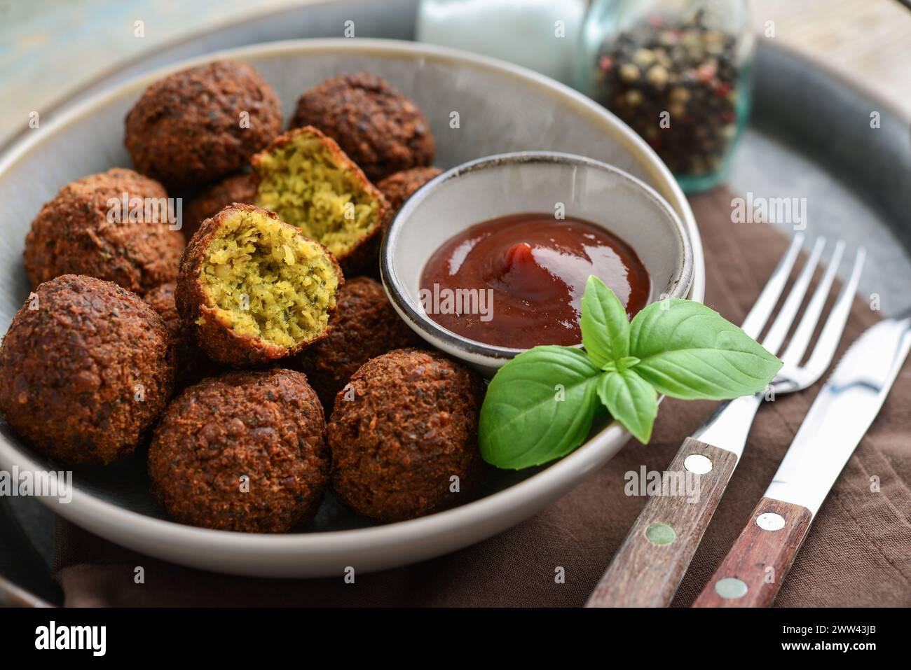 Falafelteller mit Gewürz und Suppe auf Metalltablett auf hölzernem Hintergrund, Nahaufnahme Stockfoto