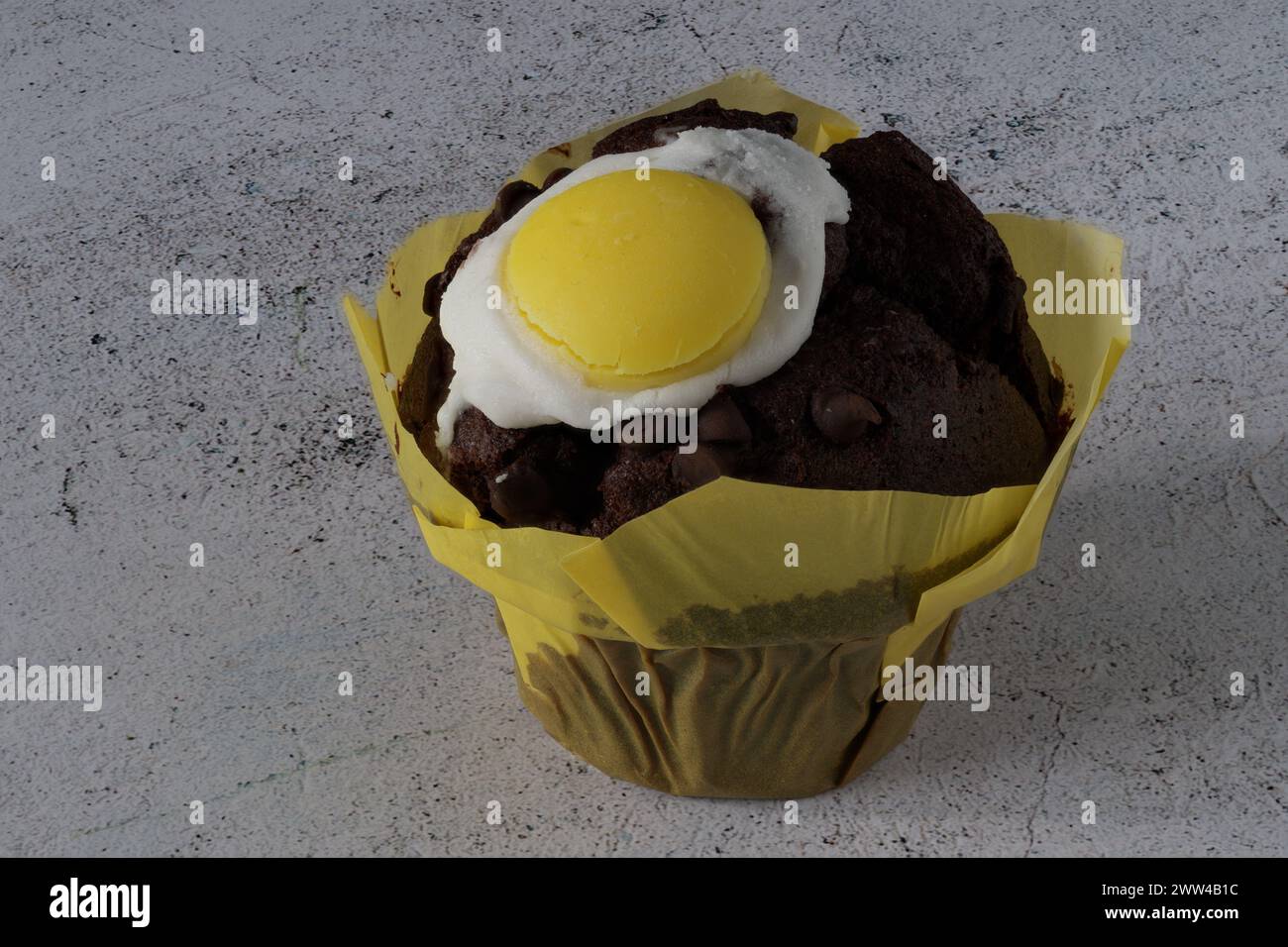 Ein Schokoladenmuffin mit Ostermotiv auf einem weißen Betontisch Stockfoto