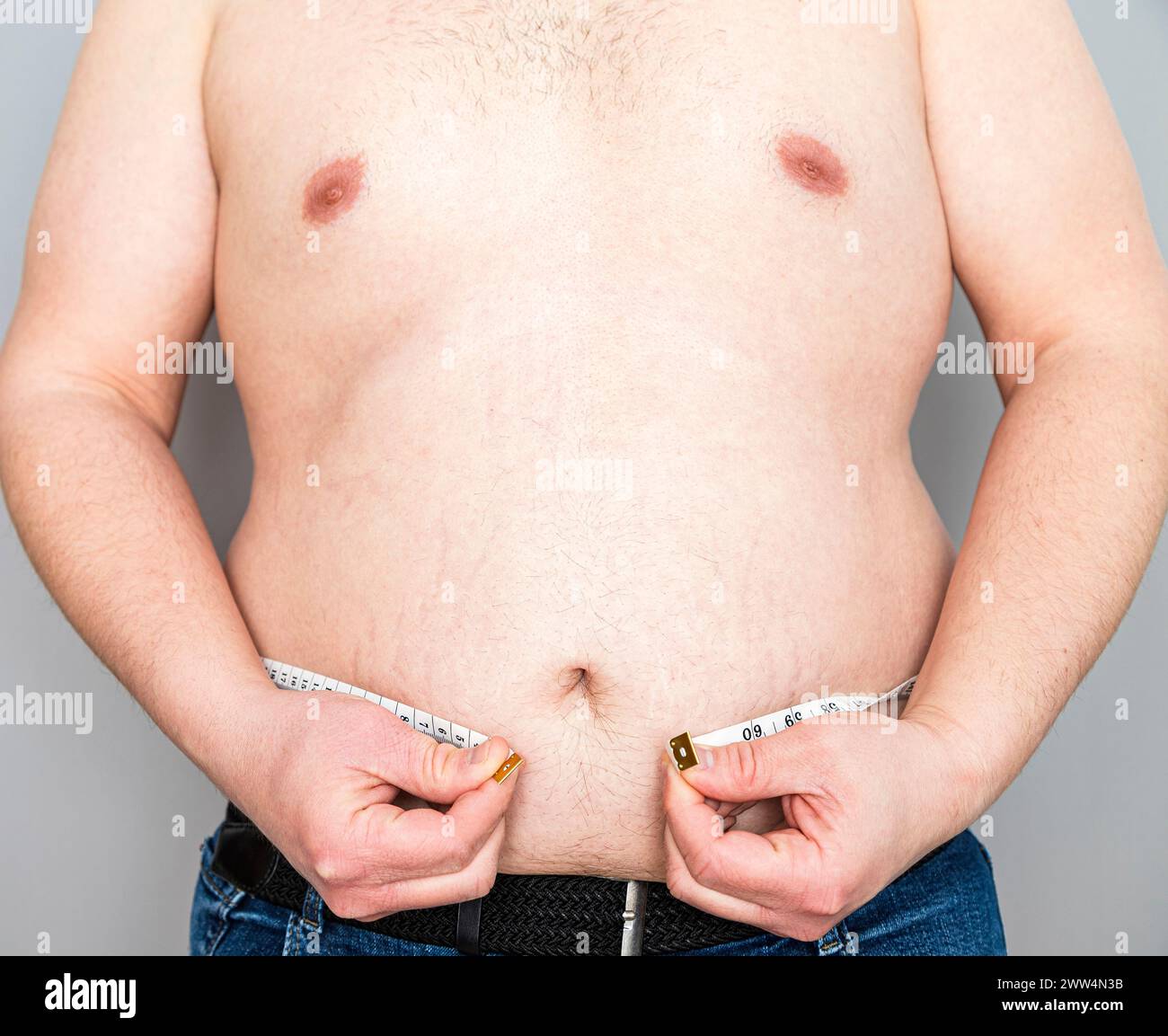 Nahaufnahme des übergewichtigen Bauches eines nicht erkennbaren kaukasischen Mannes mit einem Maßband, das nicht ausreicht, um seinen Bauch einzukreisen. Stockfoto