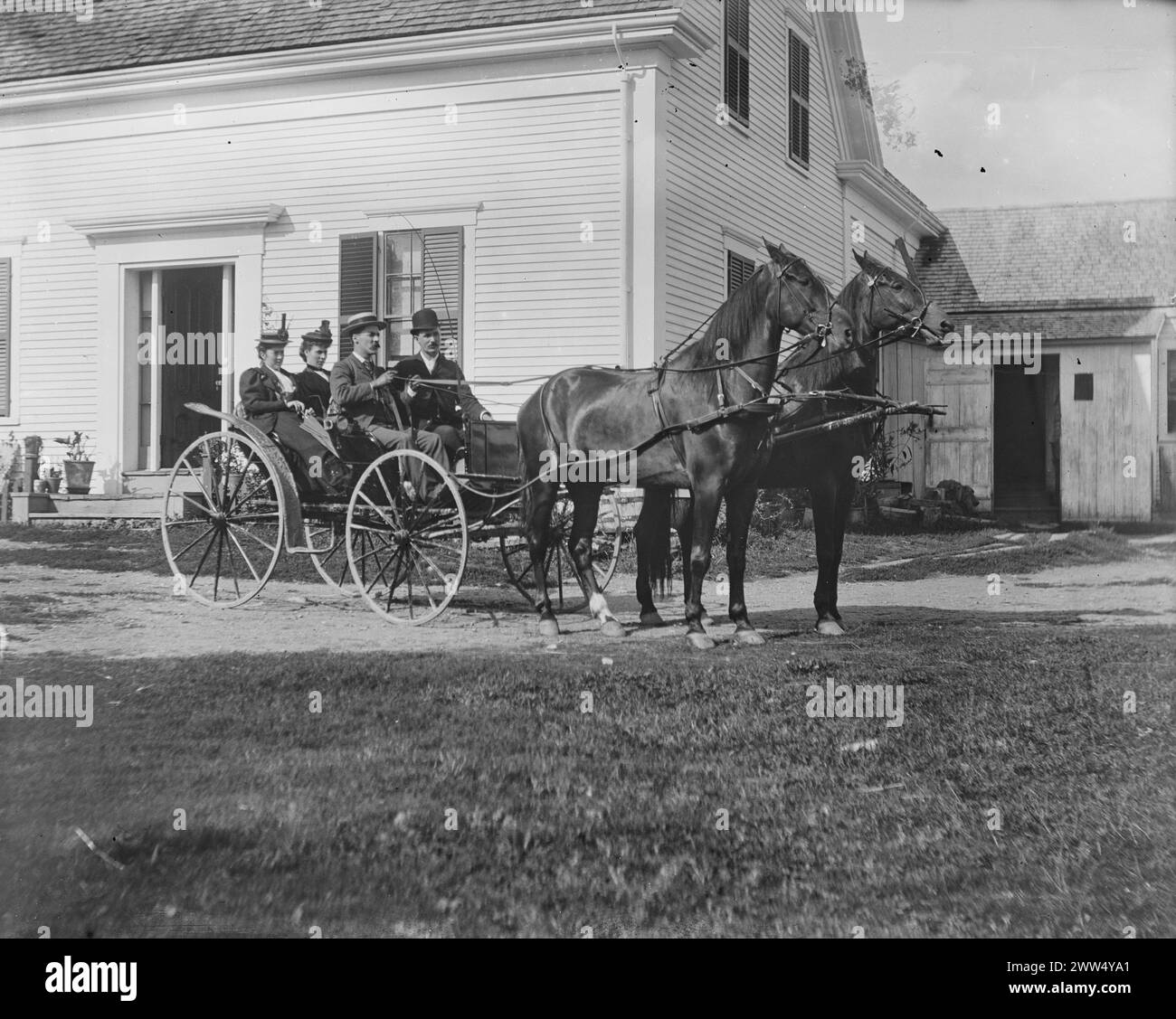 Vier Personen sitzen in einer offenen Pferdekutsche vor einem weißen Haus mit dunklen Fensterläden, schwarz-weiß abgebildet. New Brunswick, 26. August. 1893. Foto: Ervin S. Hubbard Stockfoto