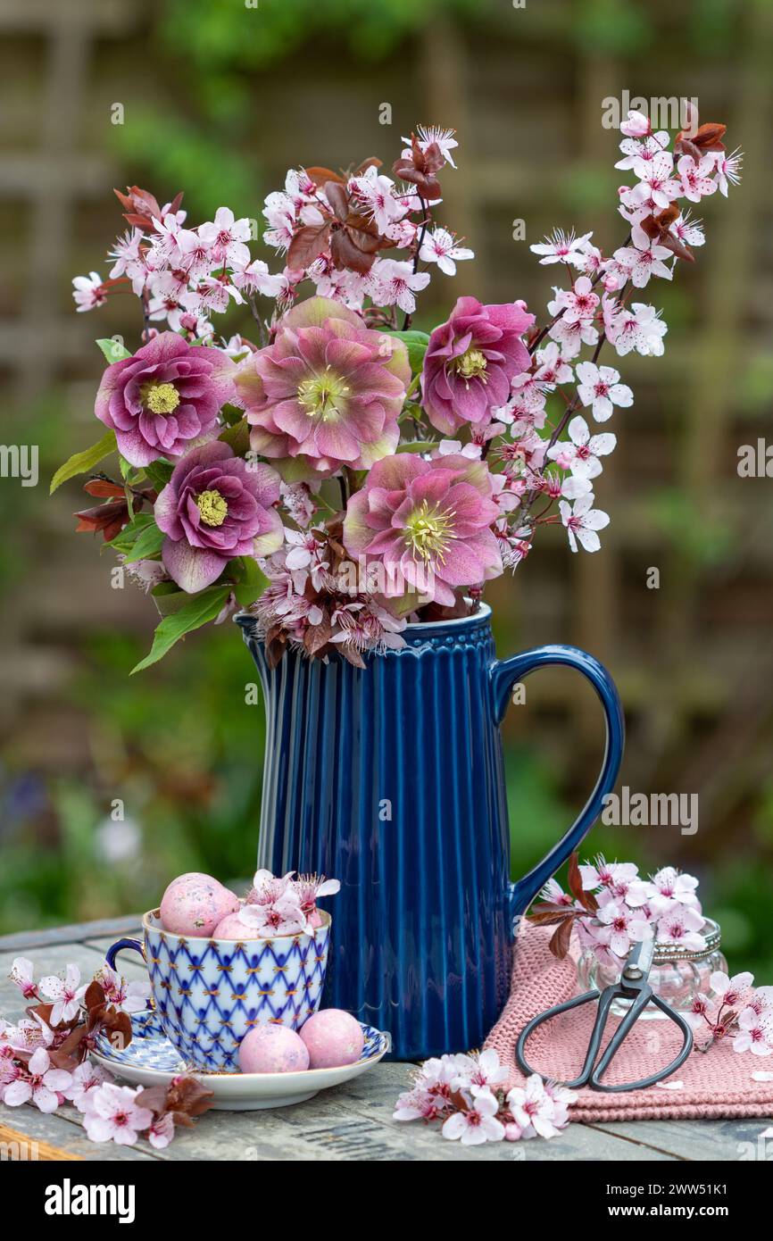 Strauß aus rosa fastenrosen und lila Pflaumenblüten in einer Vase Stockfoto