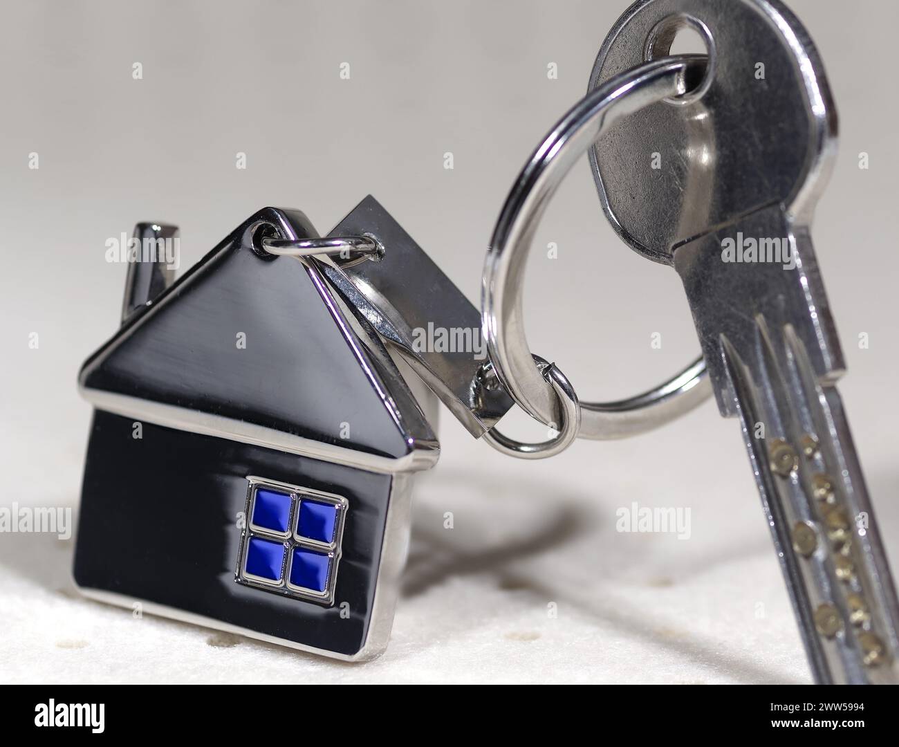 Haussymbol mit silbernen Schlüsseln auf abstraktem Hintergrund. Immobilienkonzept Stockfoto